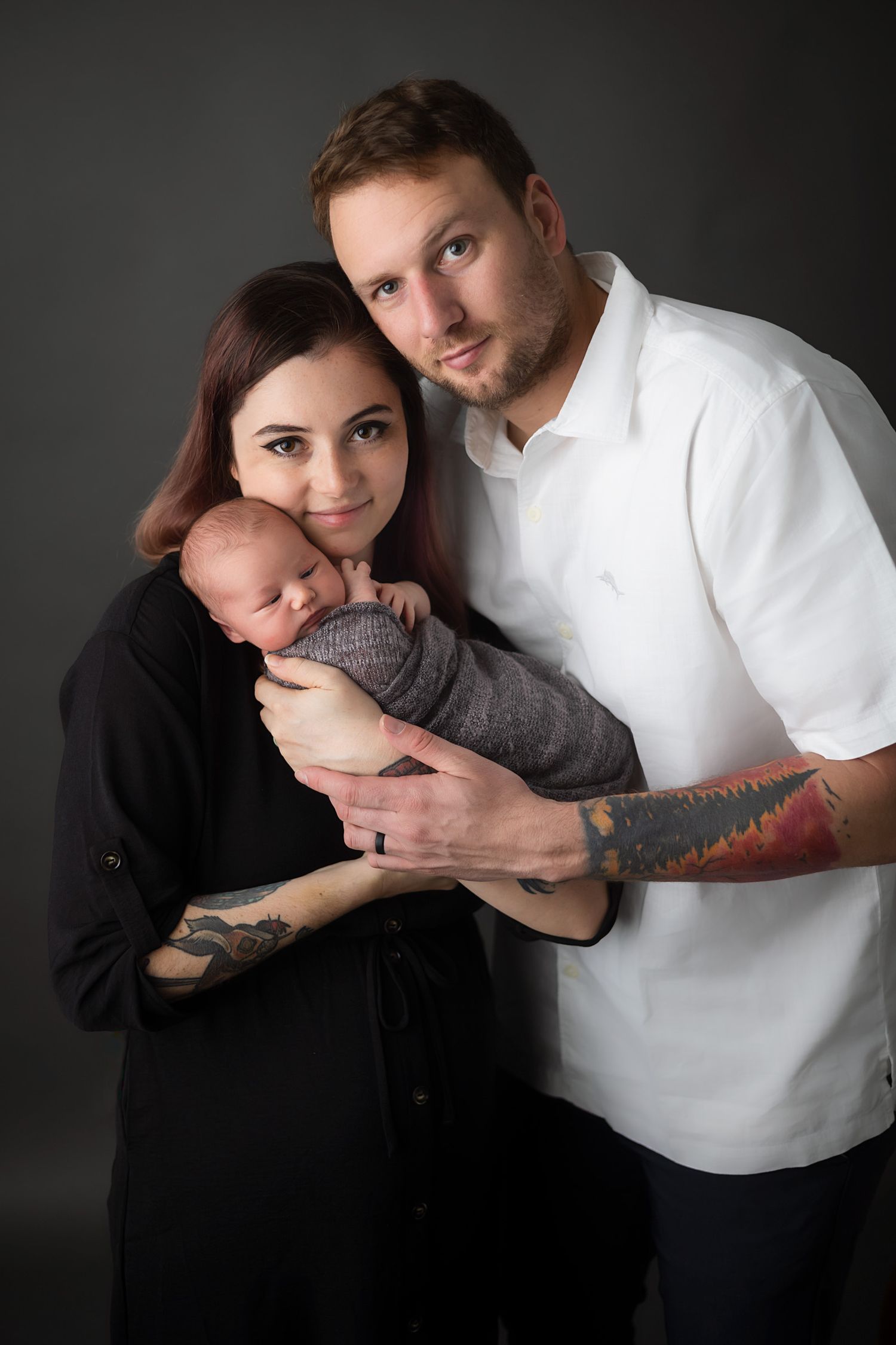 Studio portrait of parents with their newborn in black and white attire.