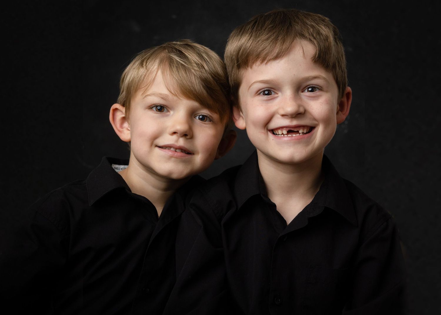 A series of black and white portraits showing joyful expressions and genuine smiles against a dark background.