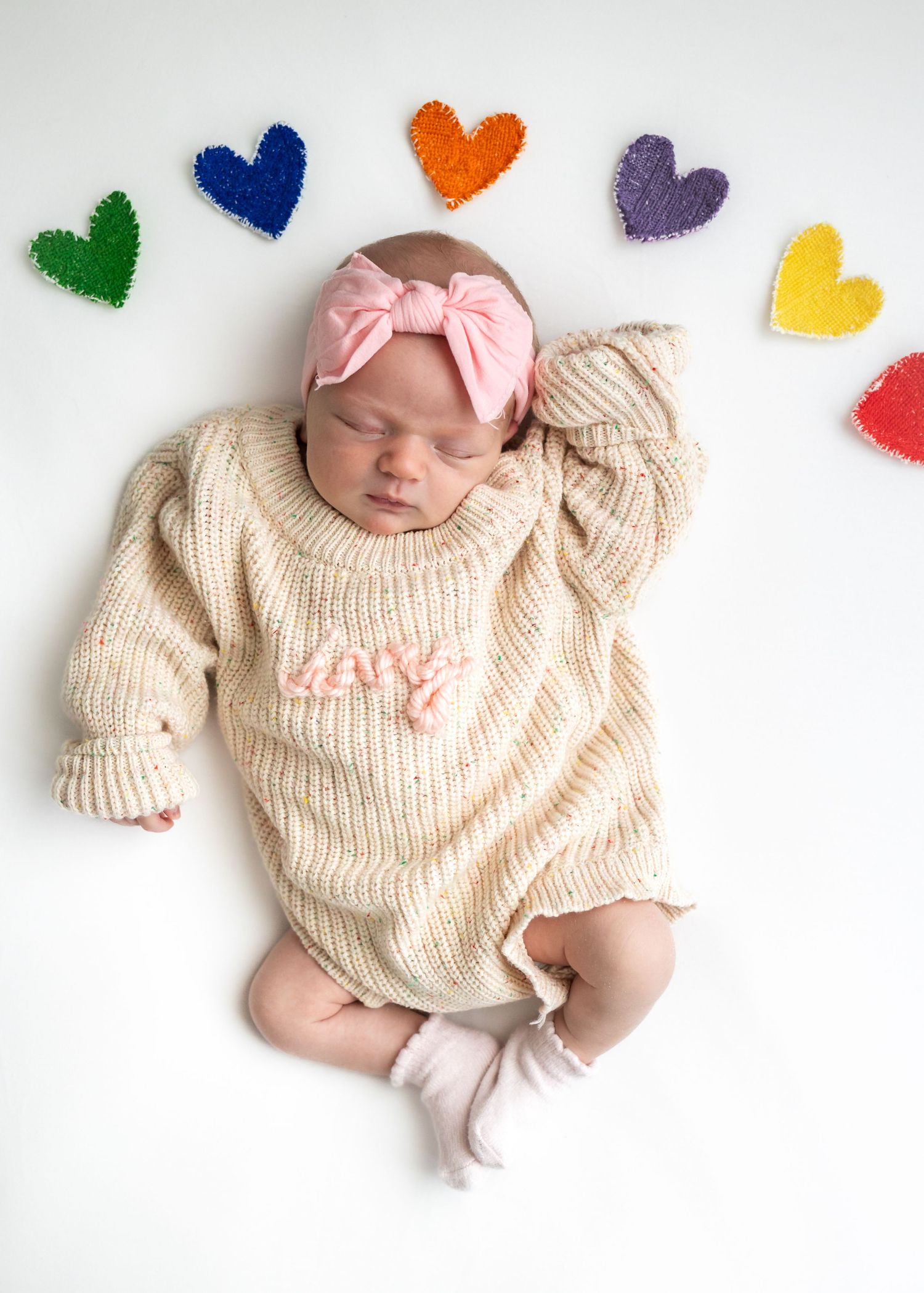 Newborn baby girl in cream knit sweater and pink bow headband, in Daleville, AL photography studio specializing in dogs, babies and families