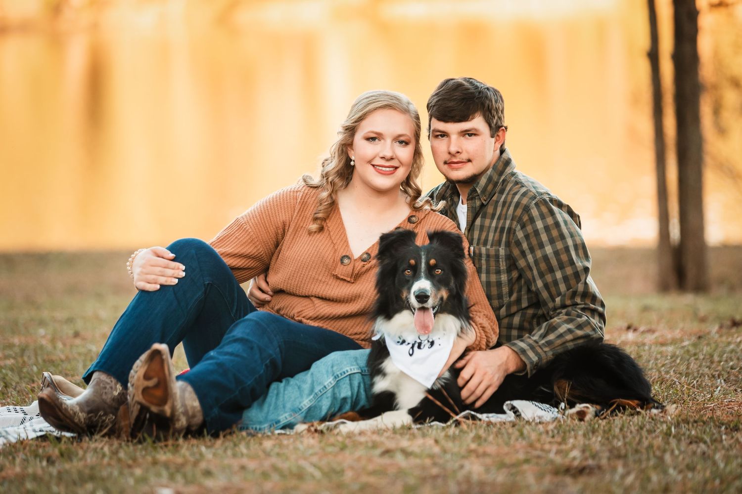 Family and dog lying together on autumn grass during golden hour outdoor photo session.