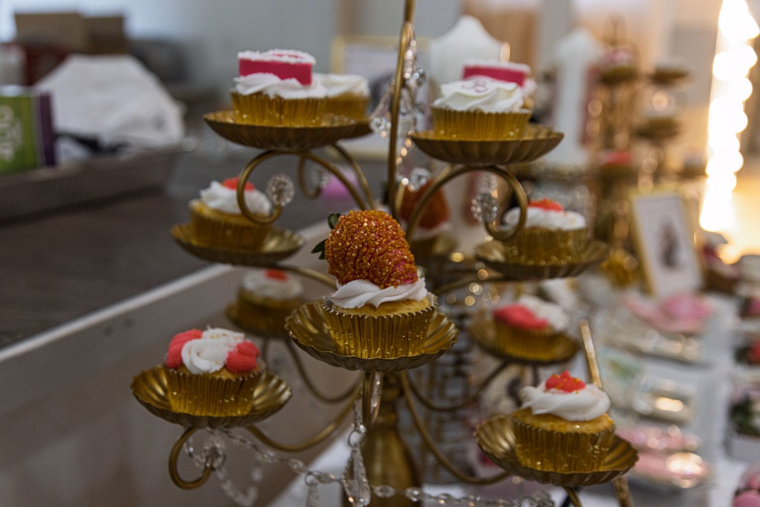 Elegant cupcakes with pink frosting decorations displayed on an ornate silver tiered serving stand.