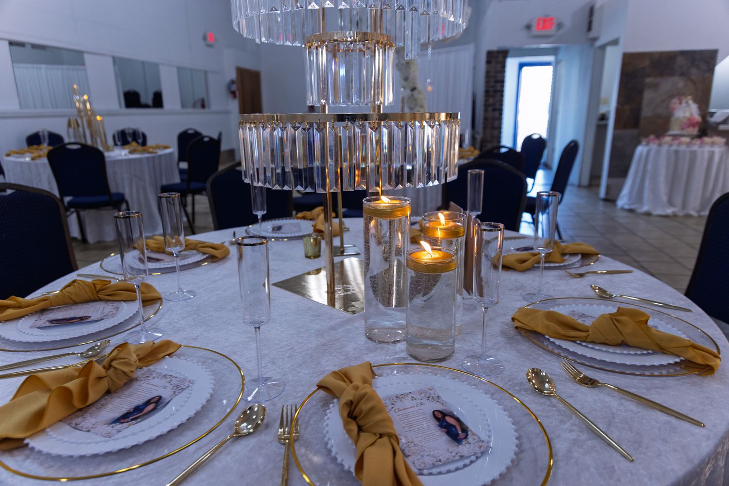 Elegant table settings with crystal chandeliers, white linens, and gold napkins in a formal dining room.