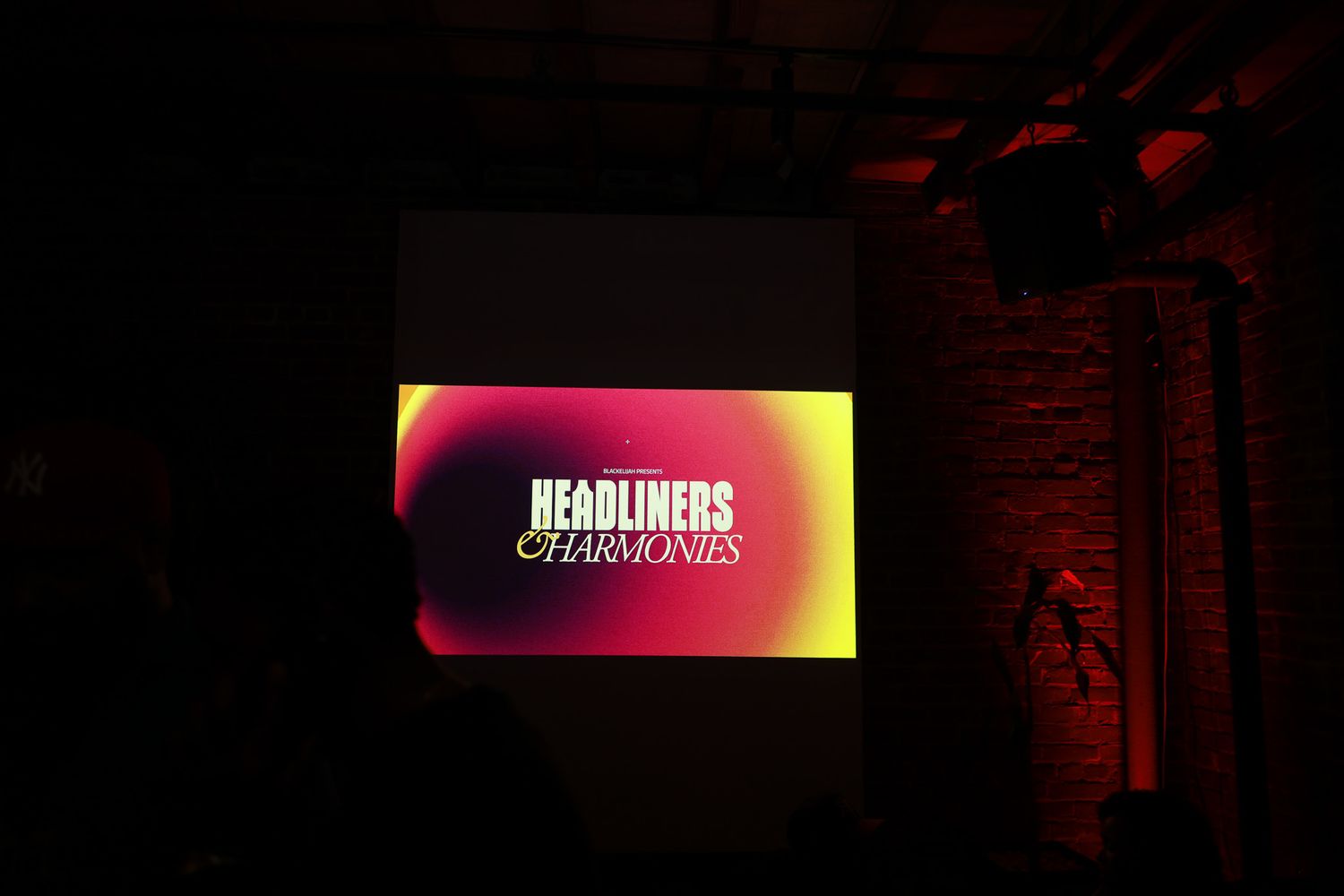 A dark concert stage illuminated by vibrant pink and purple lighting effects creates a dramatic atmosphere.