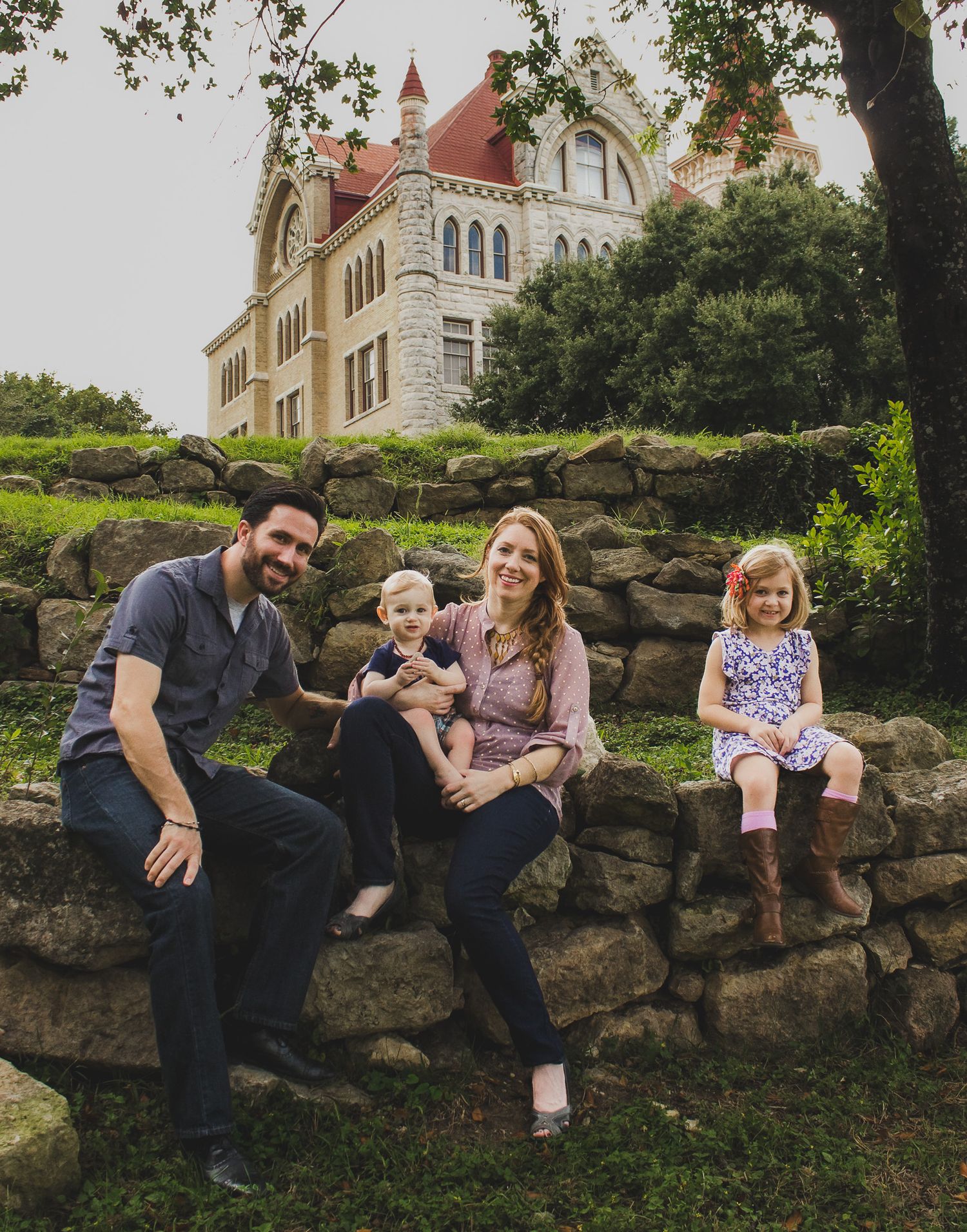 Family of four sitting together on a stone wall outdoors, relaxed natural light family portrait, Finger Lakes New York.