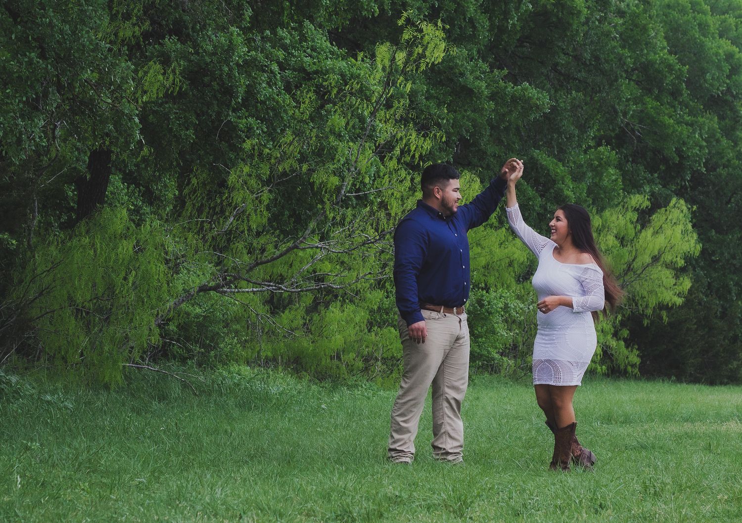 Couple dancing together in a lush green field, candid outdoor engagement portrait, Finger Lakes NY, Soft Wild Light.