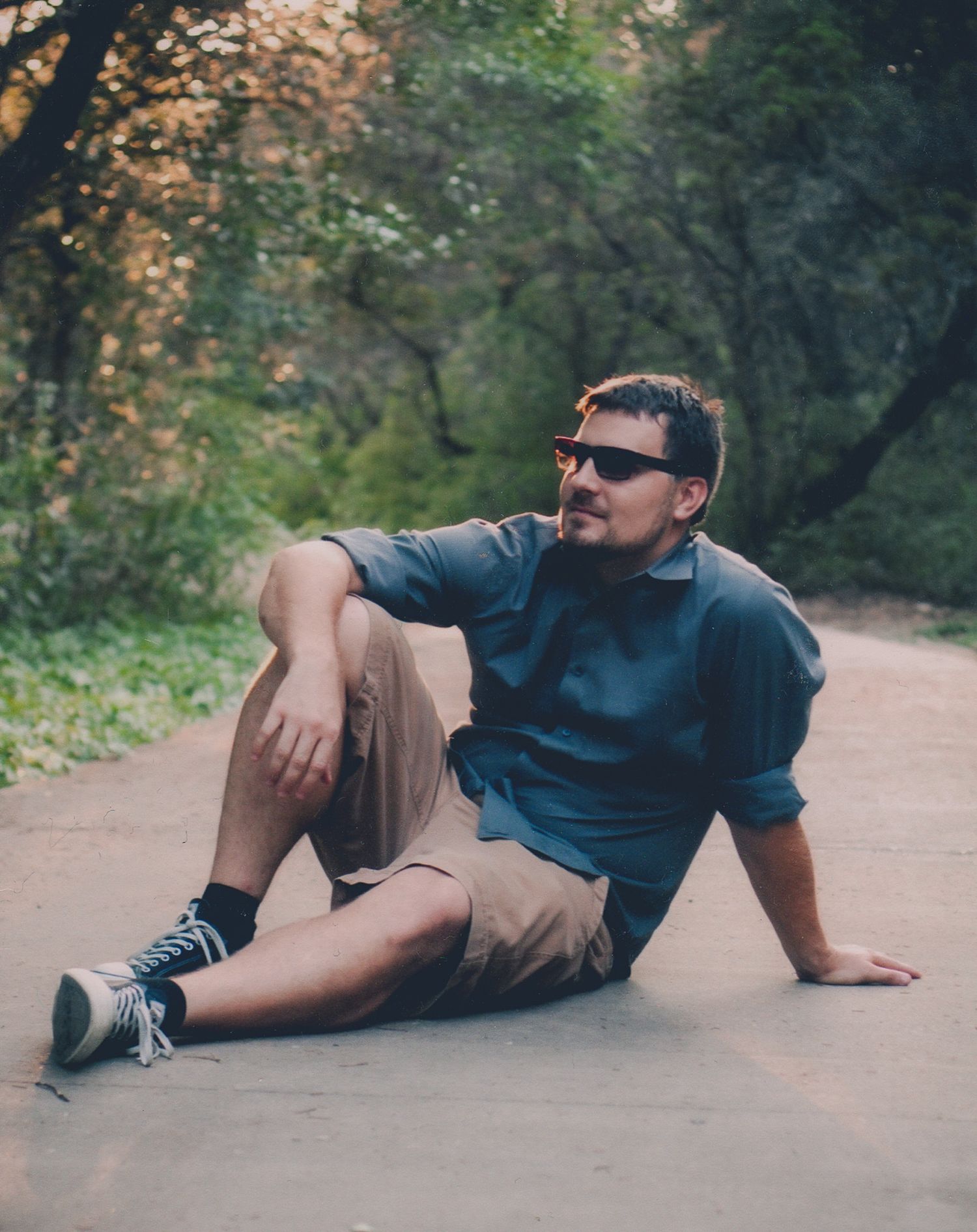 Casual portrait of a man in sunglasses sitting on an outdoor path, natural light photography, Finger Lakes NY, Soft Wild Light