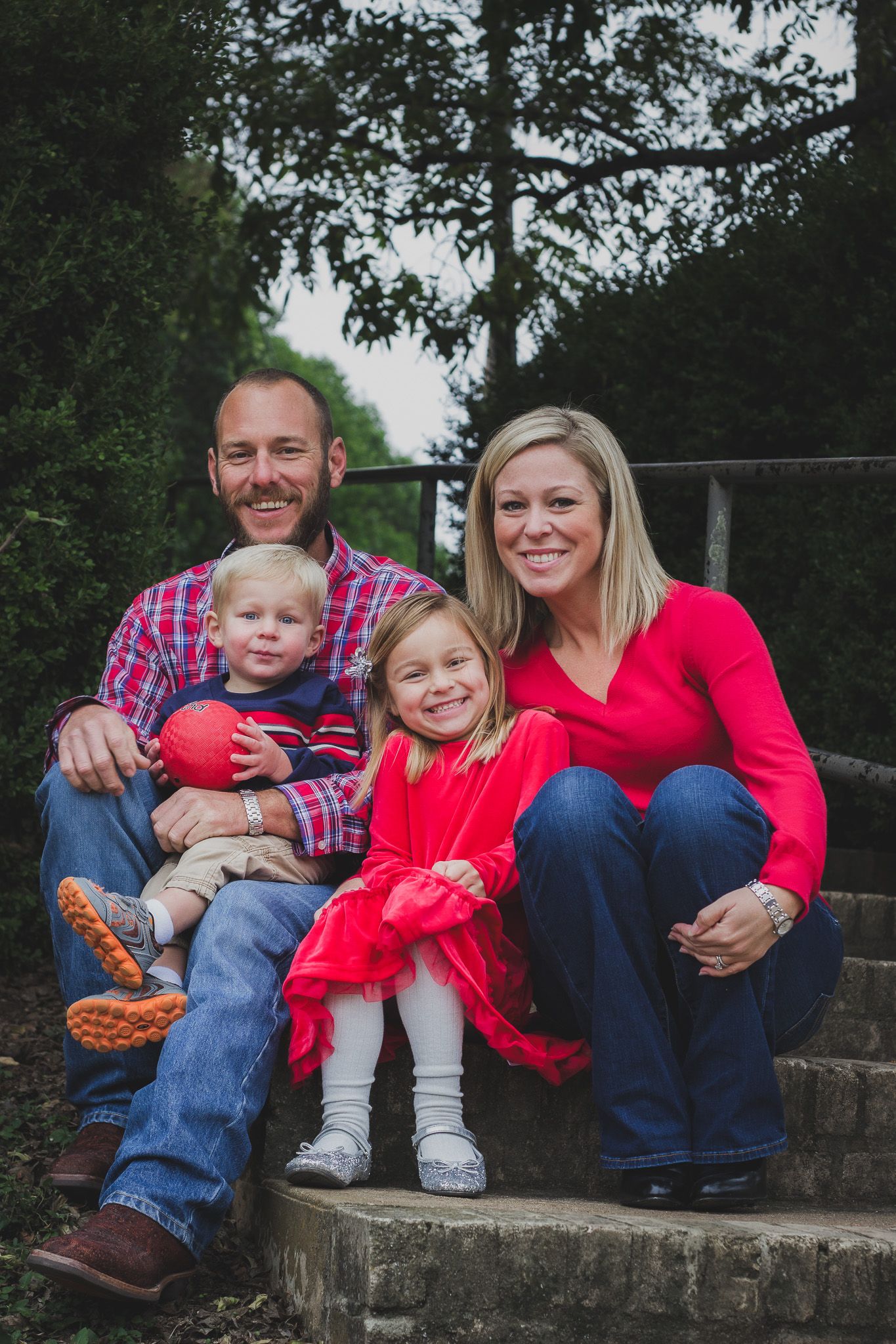 Family of four smiling and sitting together on stone steps, outdoor natural light portrait session, Finger Lakes NY, Soft Wild Light.