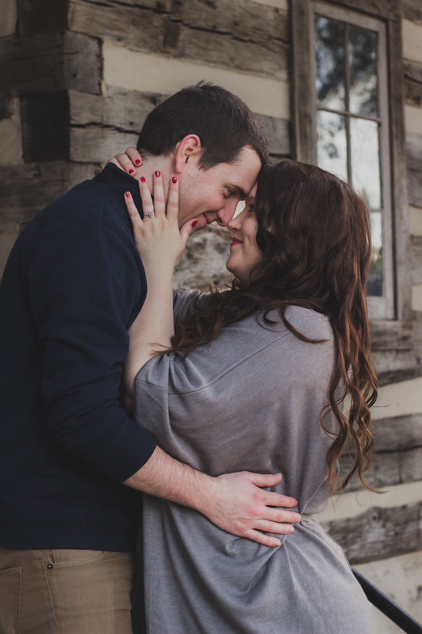 Couple sharing a kiss near a wooden cabin, natural light outdoor engagement portrait, Finger Lakes New York, Soft Wild Light Photography.