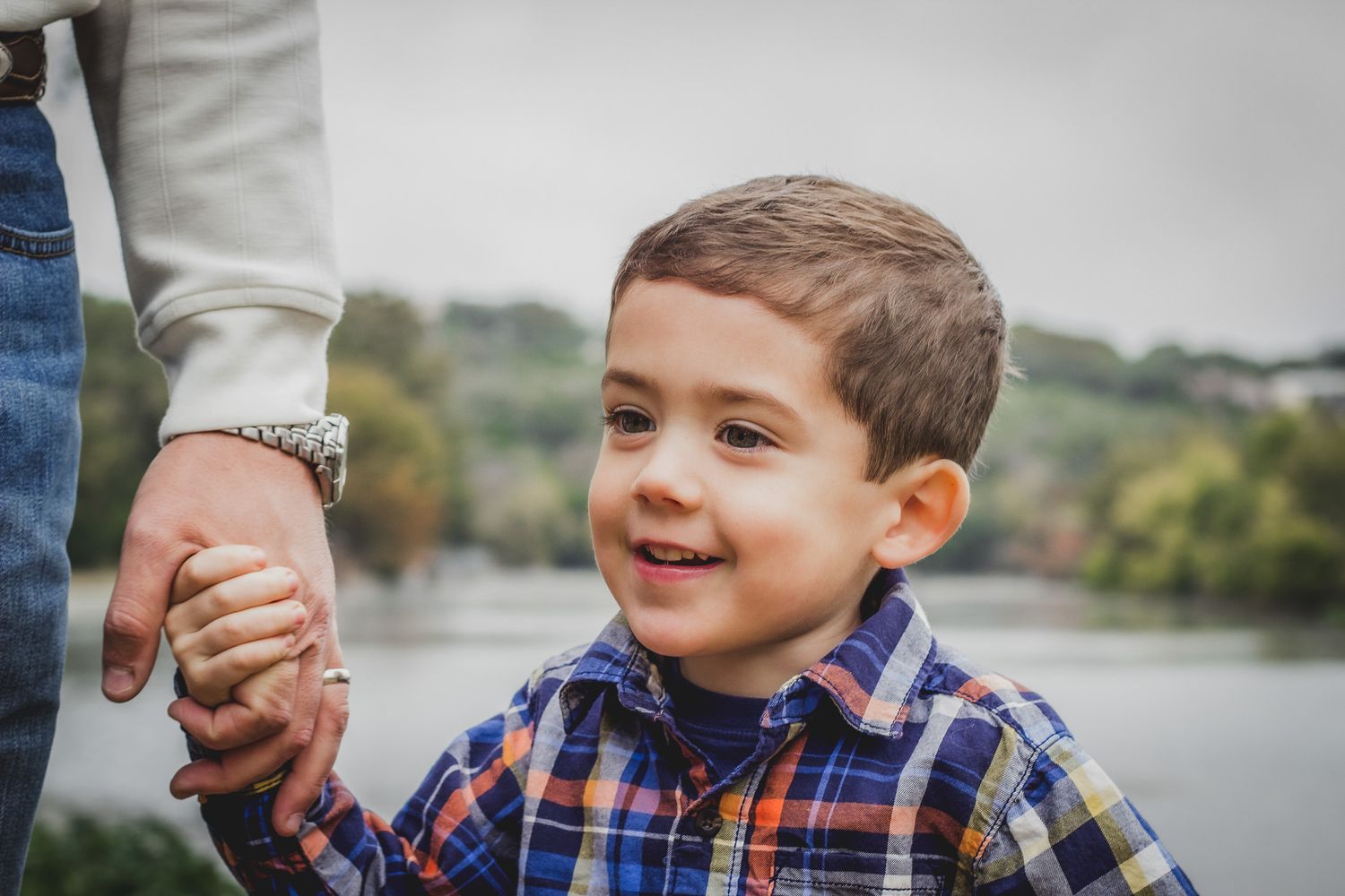 Young boy holding a parent's hand and smiling outdoors near water, natural light child portrait, Finger Lakes New York, Soft wild light.