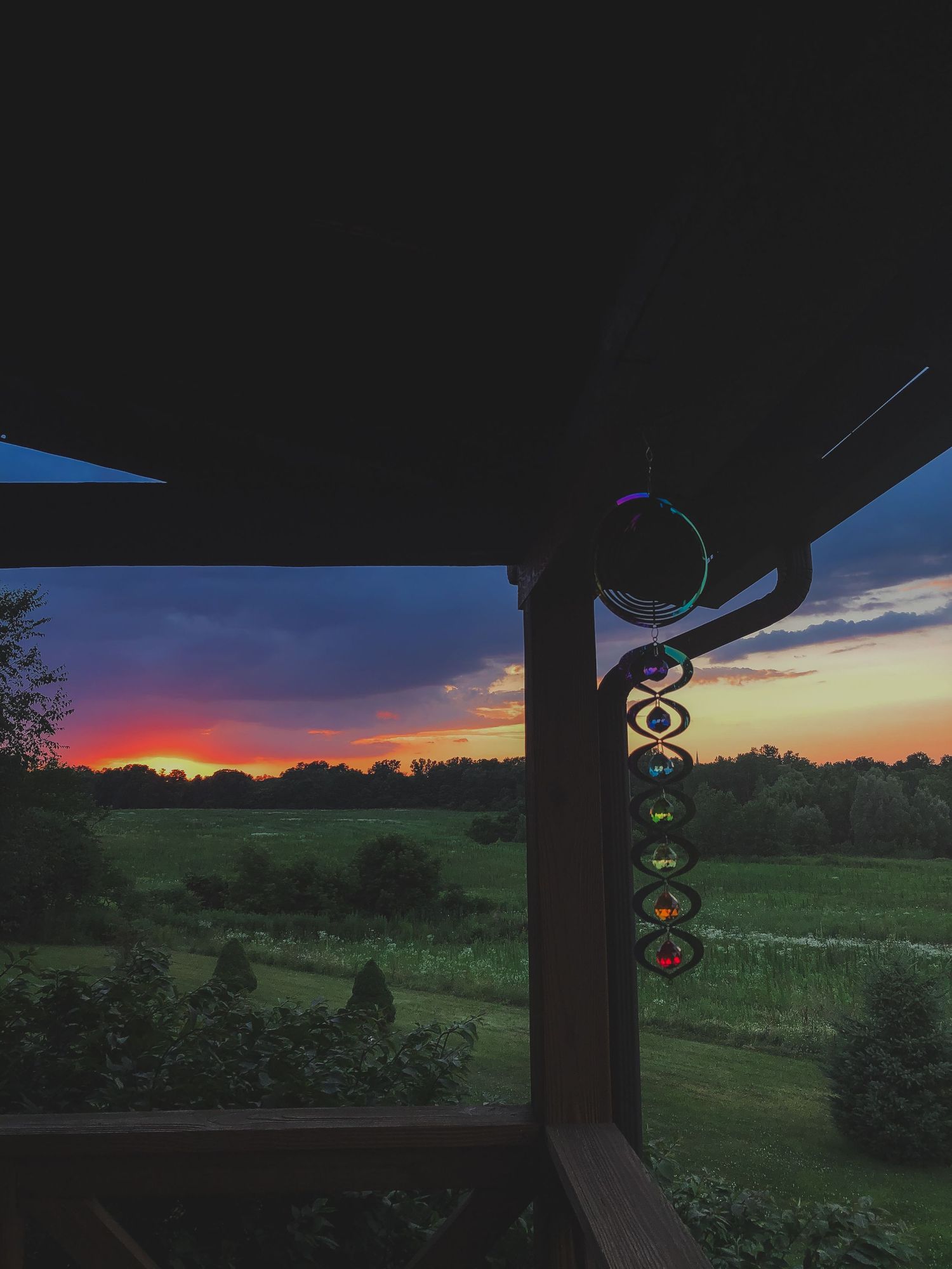 Vivid sunset over rural farmland viewed from a homestead porch, Finger Lakes NY portrait photography location.