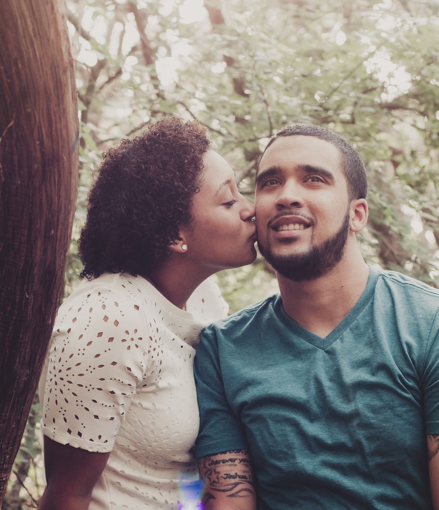 Woman kissing man's cheek in a tender couples portrait, natural light outdoor photography, Finger Lakes NY, Soft Wild Light.