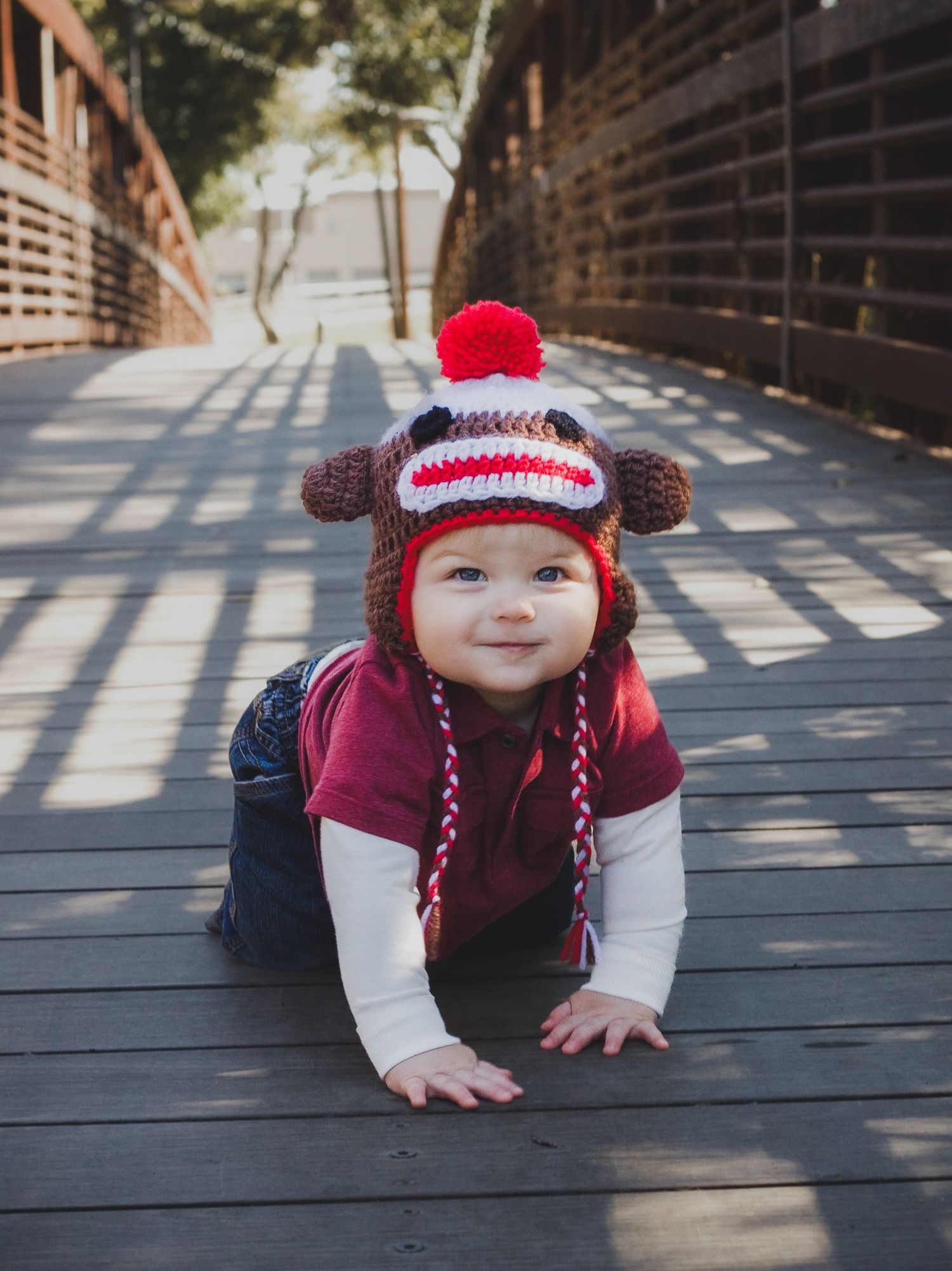 Baby in a knit hat crawling on a wooden bridge, natural light infant portrait, Finger Lakes NY, Soft Wild Light.
