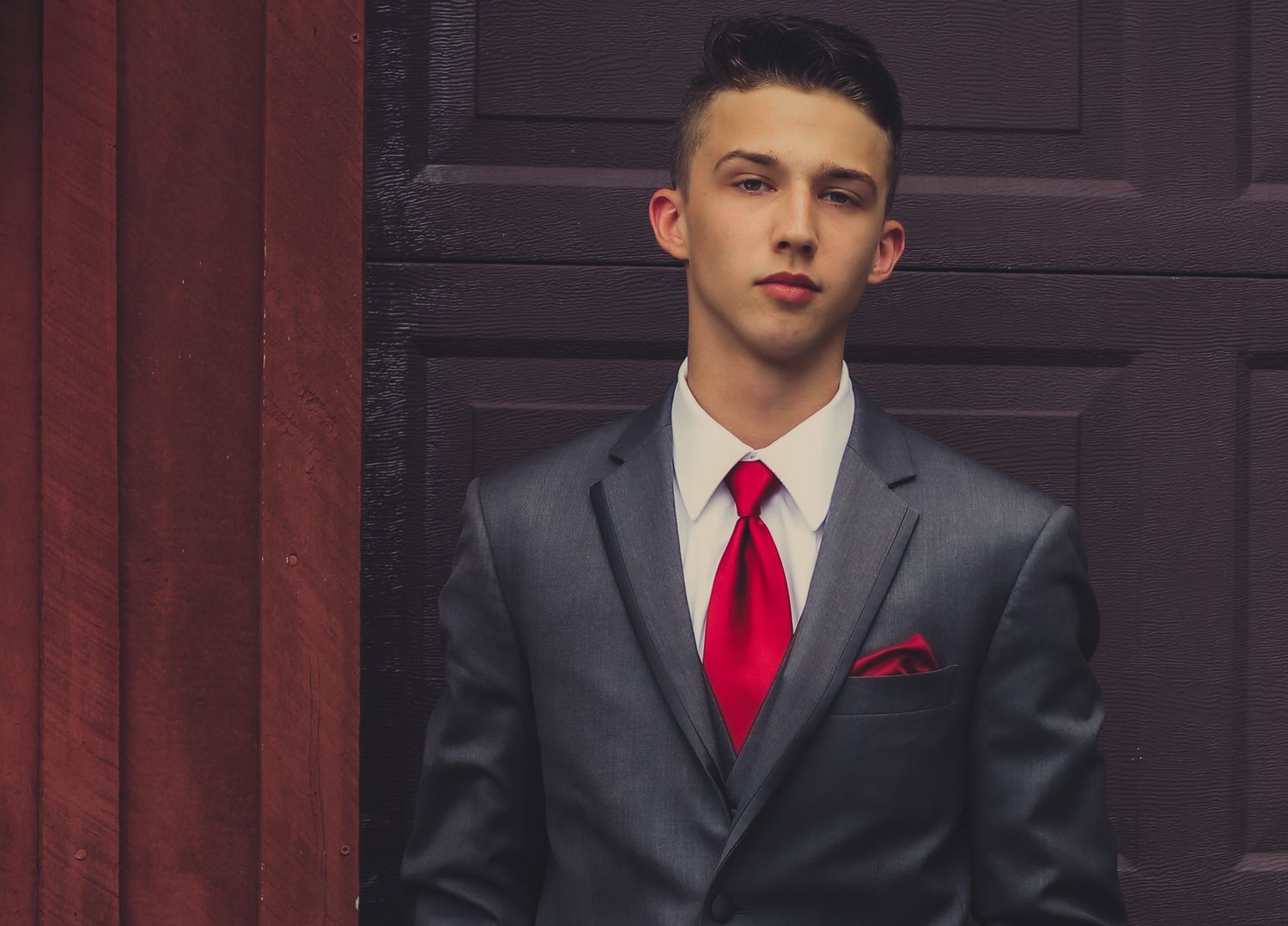 Formal senior prom portrait of a teenage boy in a suit with a red tie, outdoor natural light photography, Finger Lakes NY, Soft Wild Light.