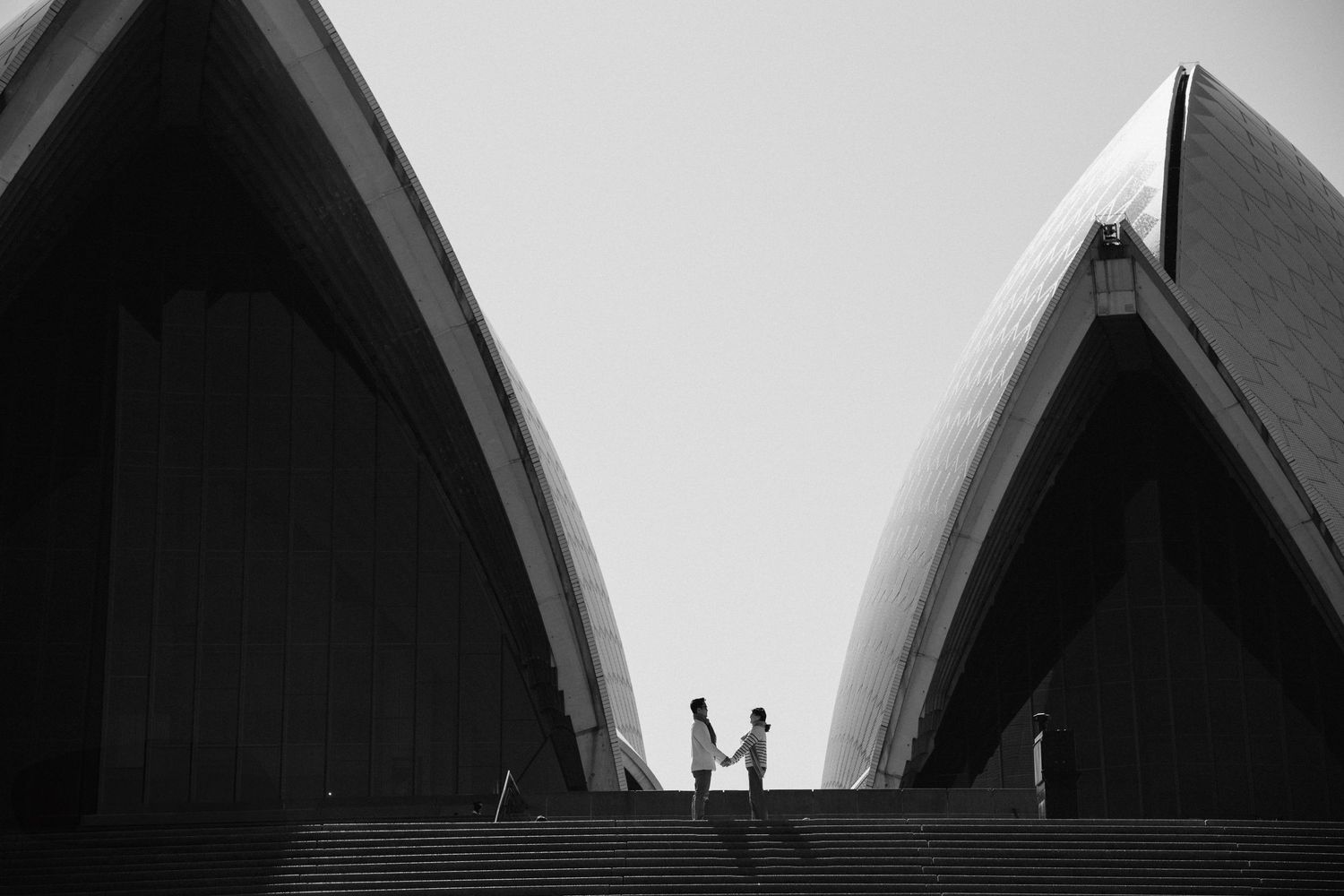 A black and white architectural photograph shows a series of arched Gothic windows in a repeating pattern.