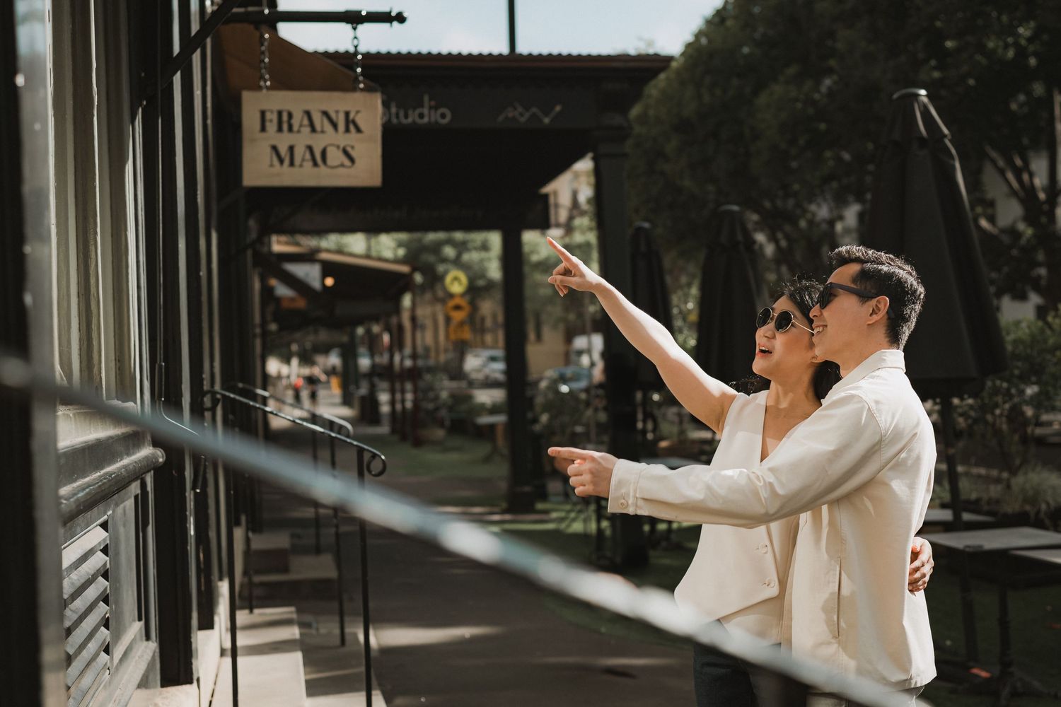 Wedding couple poses for photos in front of a Frank Black sign in an urban setting.