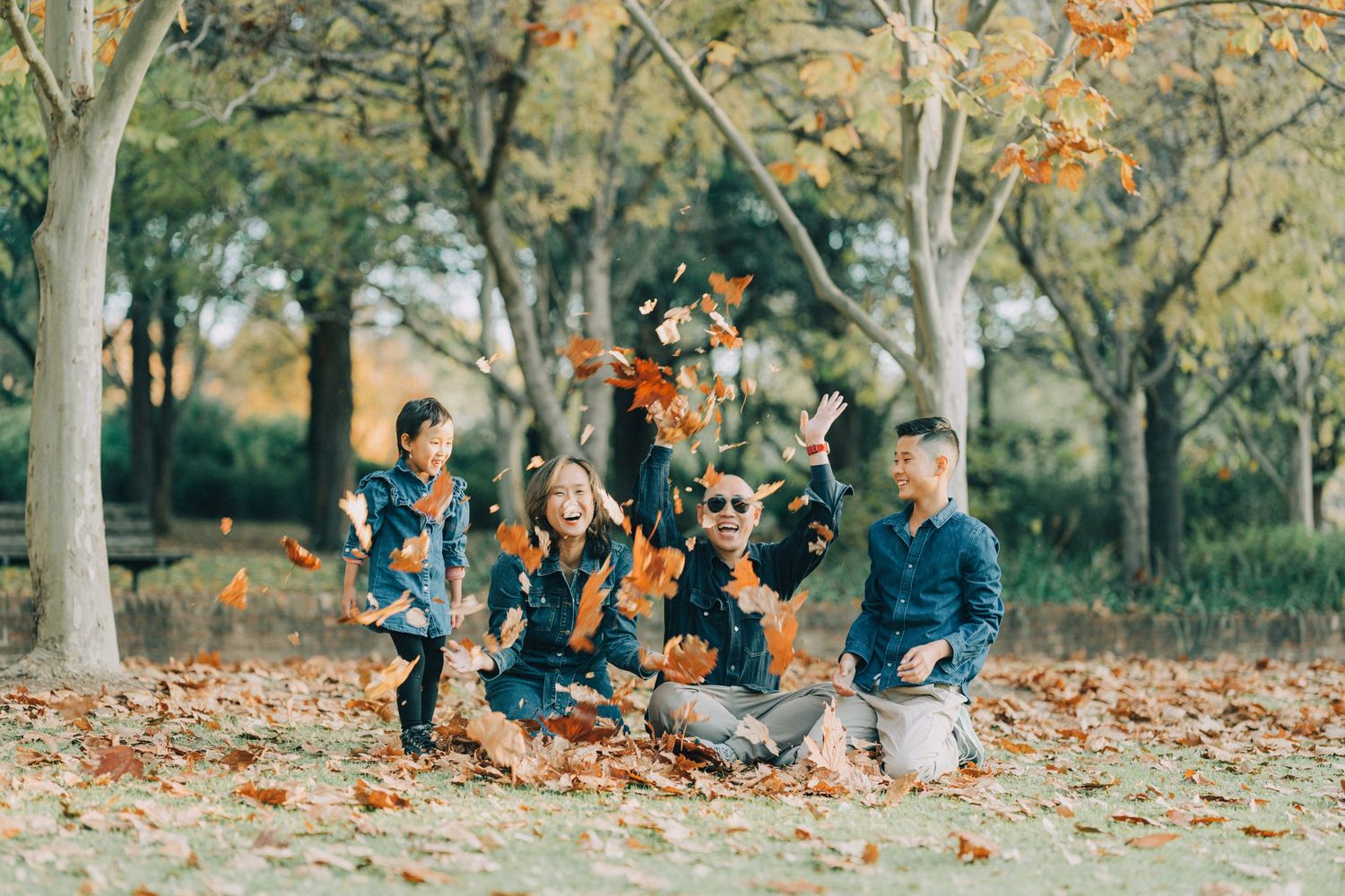 People enjoying a fall day in the park surrounded by scattered autumn leaves on the ground.
