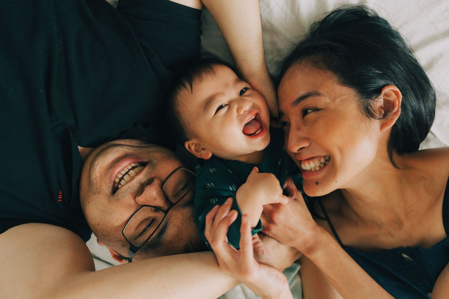 A series of candid black and white photos showing tender family moments between parent and child lying down together.