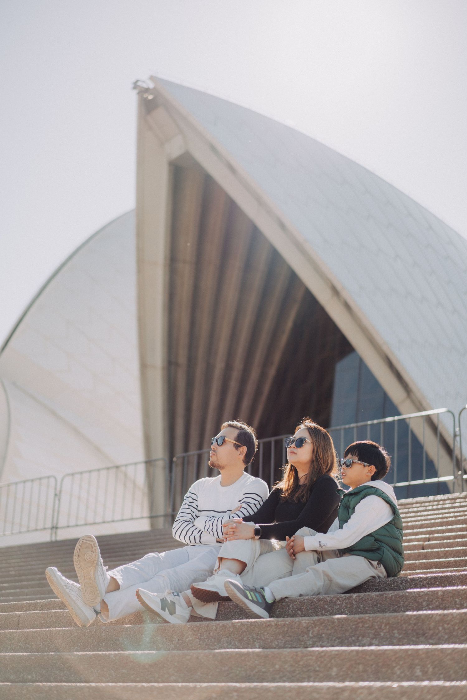 A group relaxes on the steps of the iconic Sydney Opera House in Australia during a sunny day.