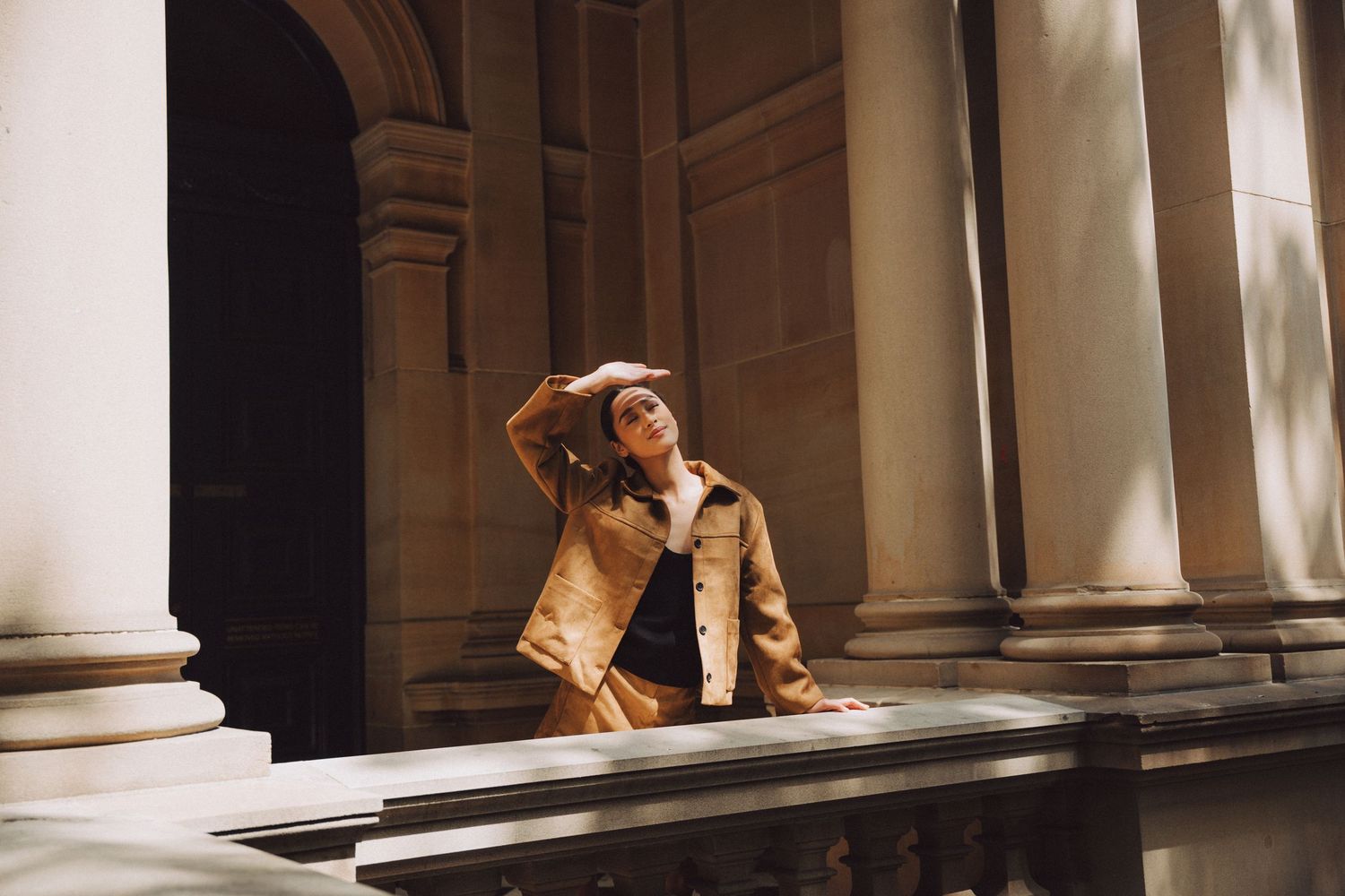 Artistic photoshoot in classical architecture setting with dramatic natural lighting.