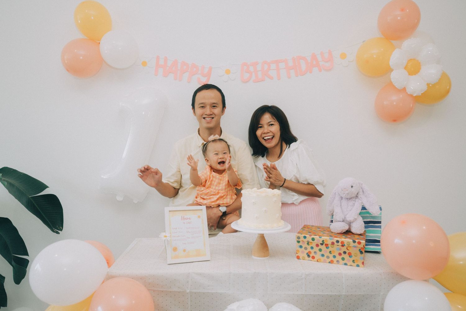 Peach and coral balloon decorations with tropical leaves create a festive party atmosphere against a white backdrop.