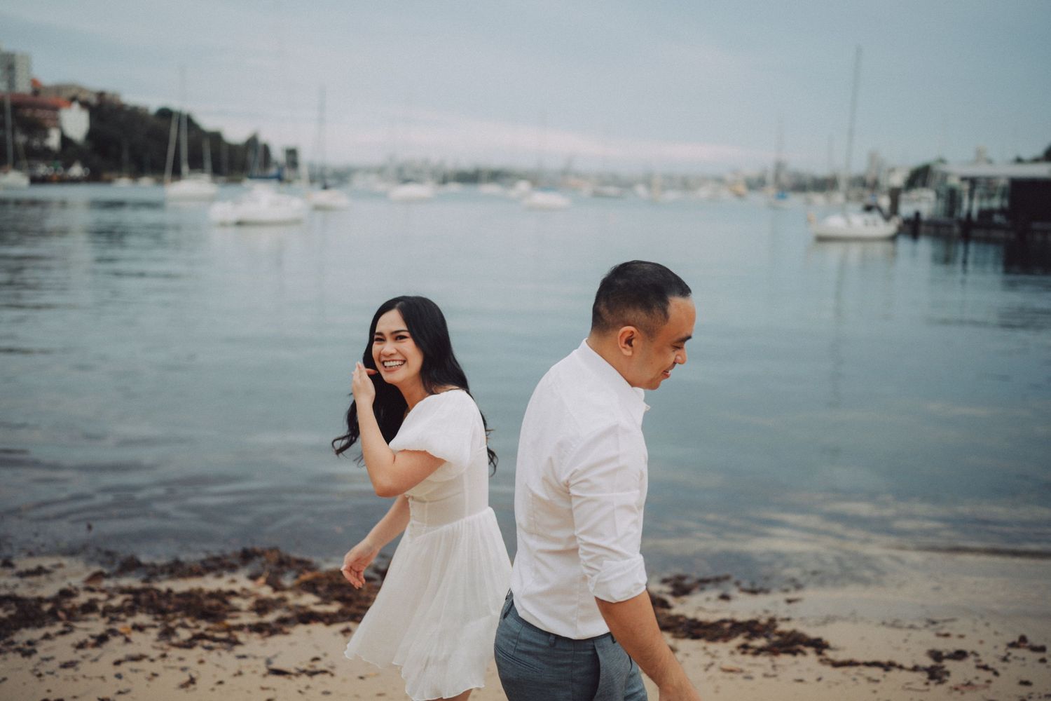 A couple poses together by the waterfront during their engagement photo session at sunset.