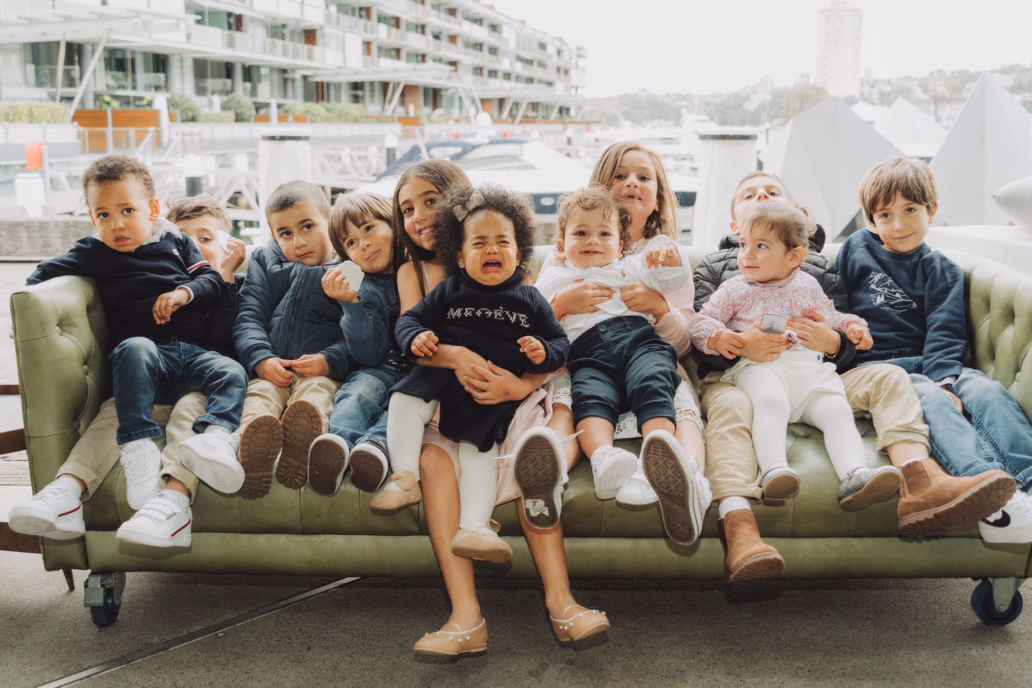 A row of people sitting together on a couch wearing casual clothing and showing their feet.