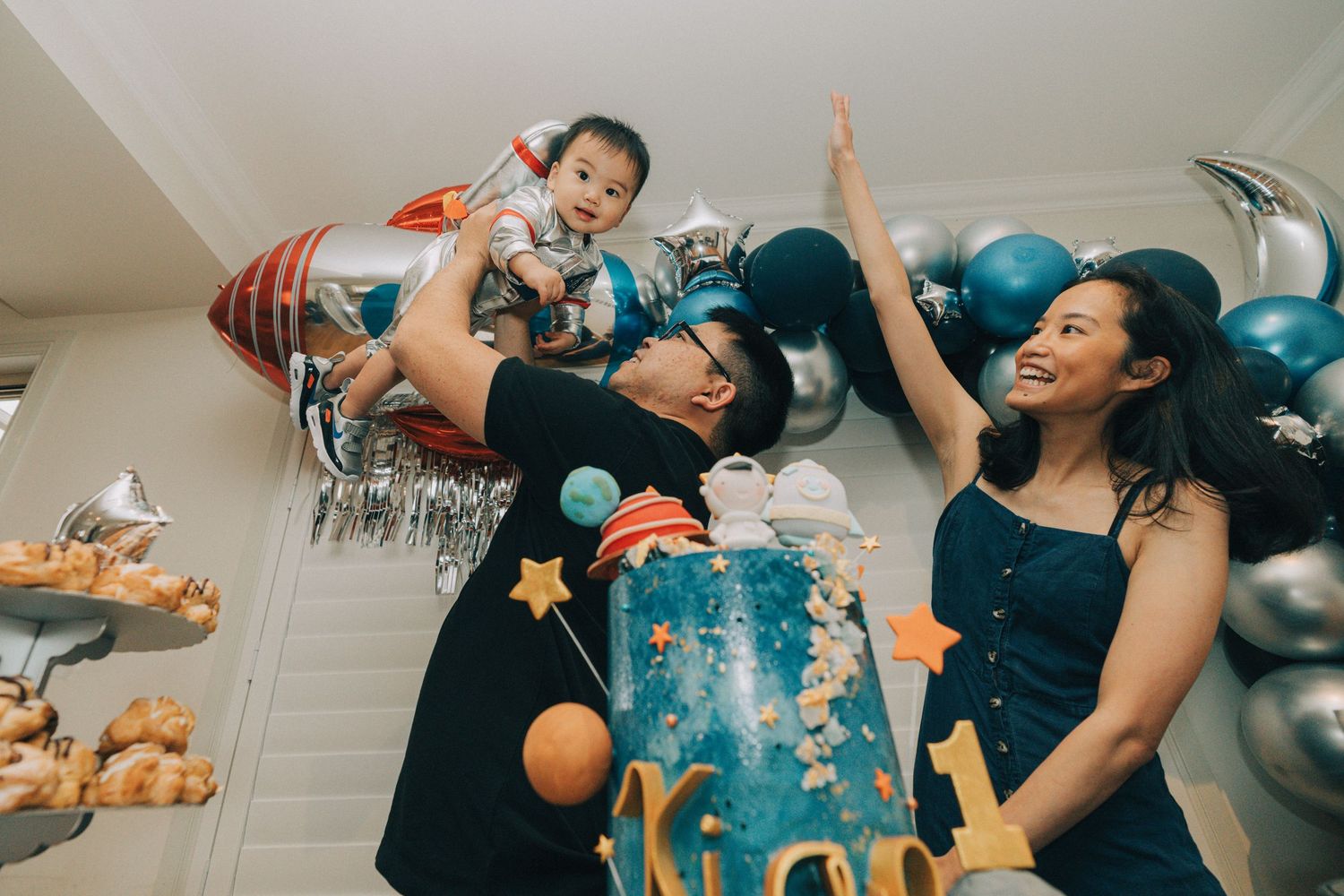 A group of people throw bread loaves in the air during a playful indoor photo sequence.
