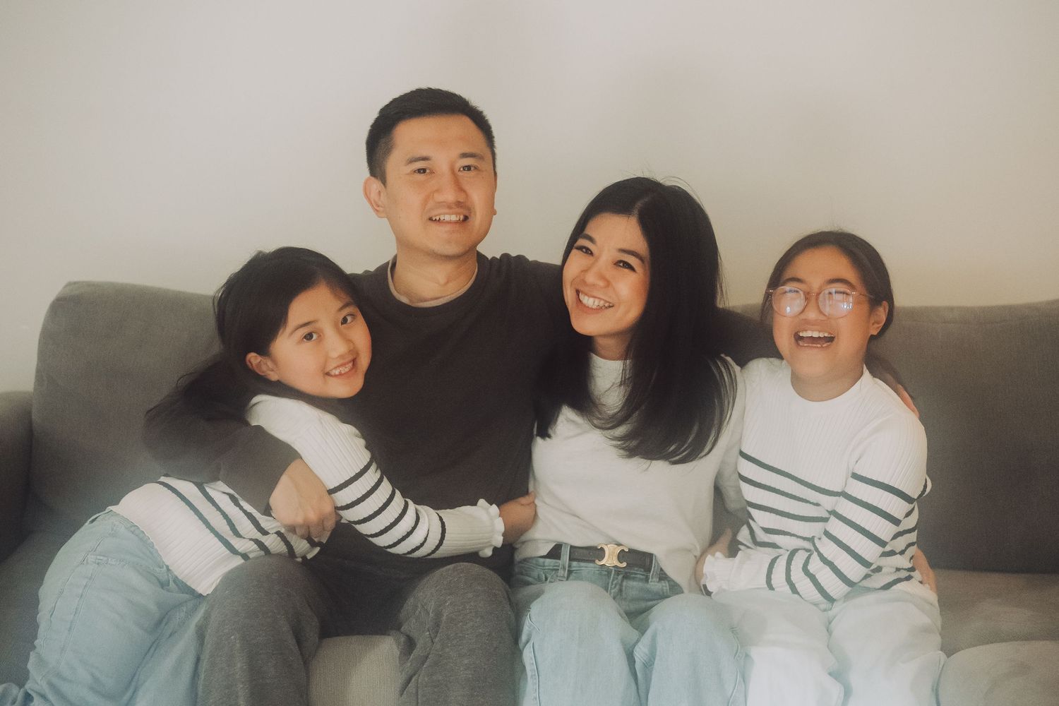 A group of friends wearing matching striped shirts share joyful moments together on a couch.