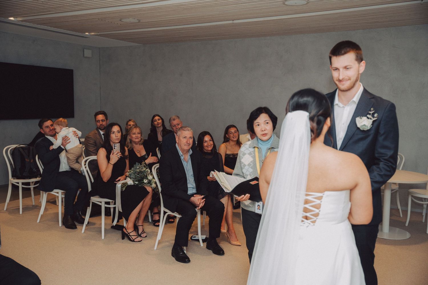 Wedding guests watch as a couple shares their first dance in a modern indoor venue.