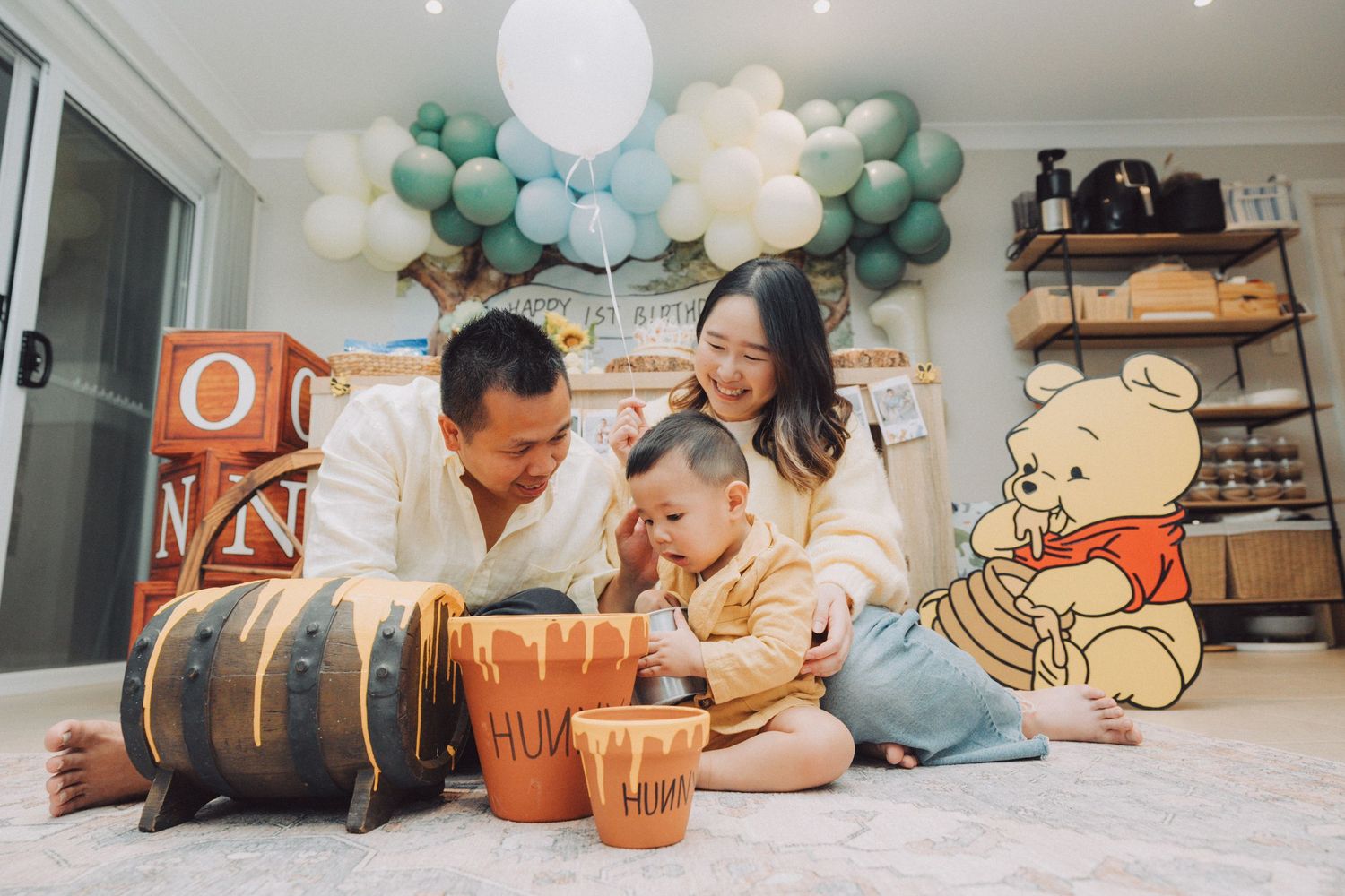 Family celebrates with drums and balloons in a cozy living room decorated with green and white party decorations.