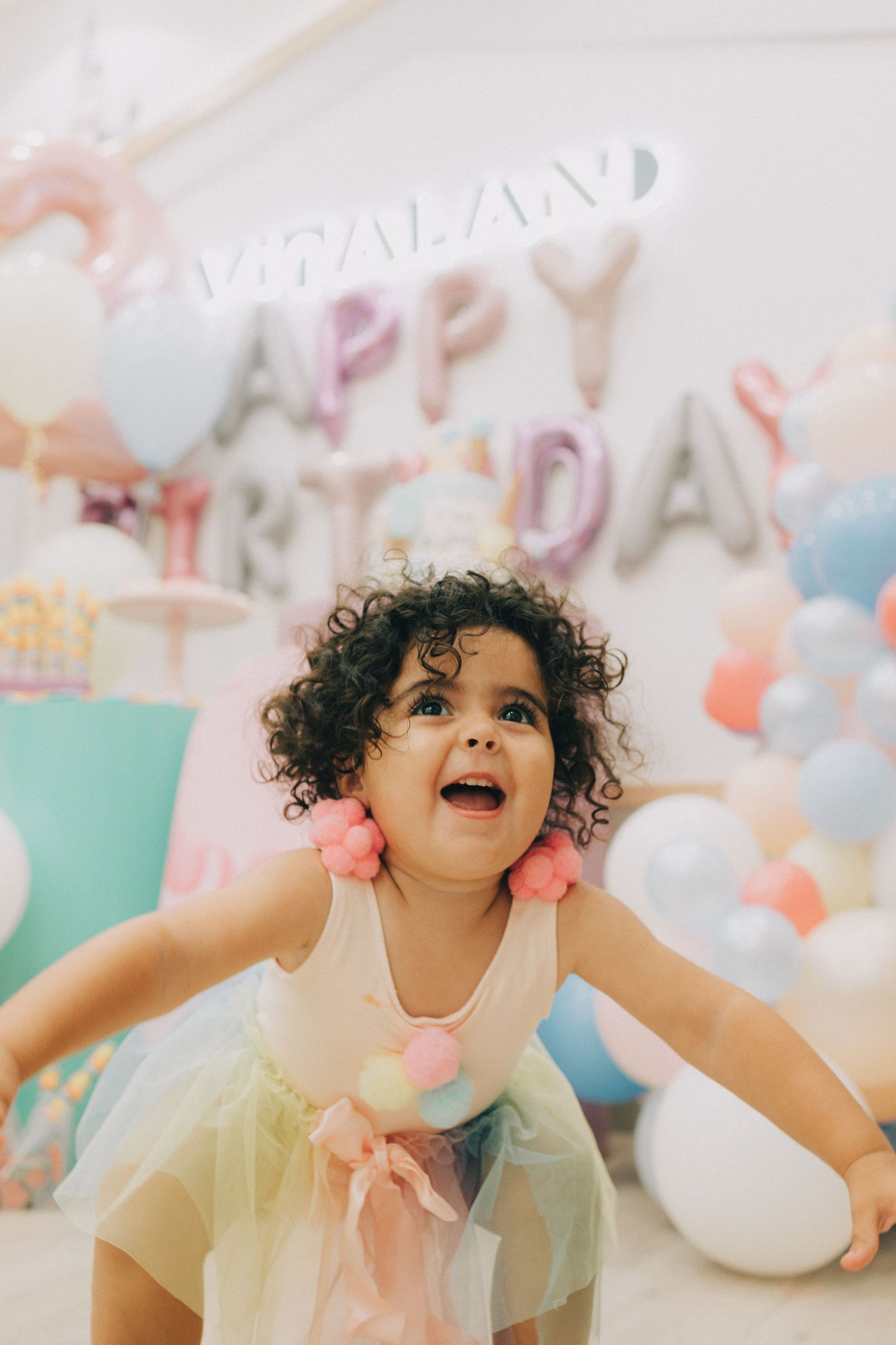 A child wearing a yellow tulle dress laughs joyfully during a whimsical birthday party celebration.