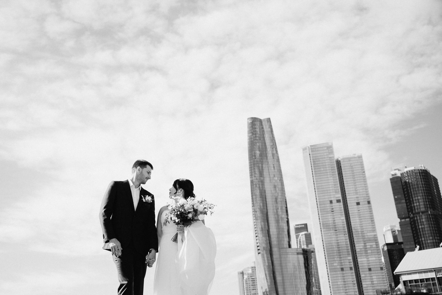 A couple shares a romantic moment against the backdrop of a modern city skyline in black and white.
