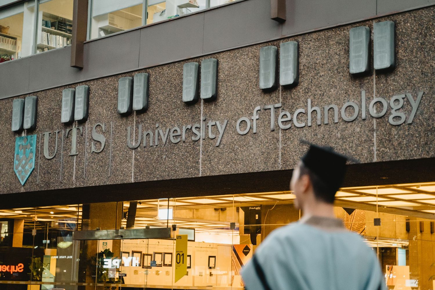 Students gather in a modern university hallway with illuminated signs and display cases along the walls.