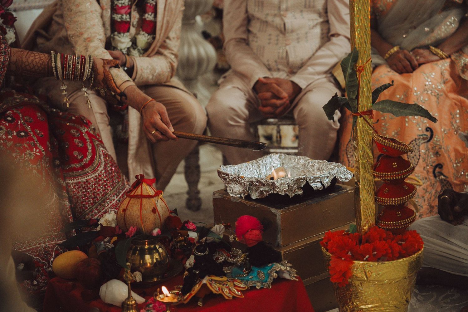 Traditional Hindu wedding ceremony with sacred ritual items, fire altar, and couple in vibrant ceremonial attire.