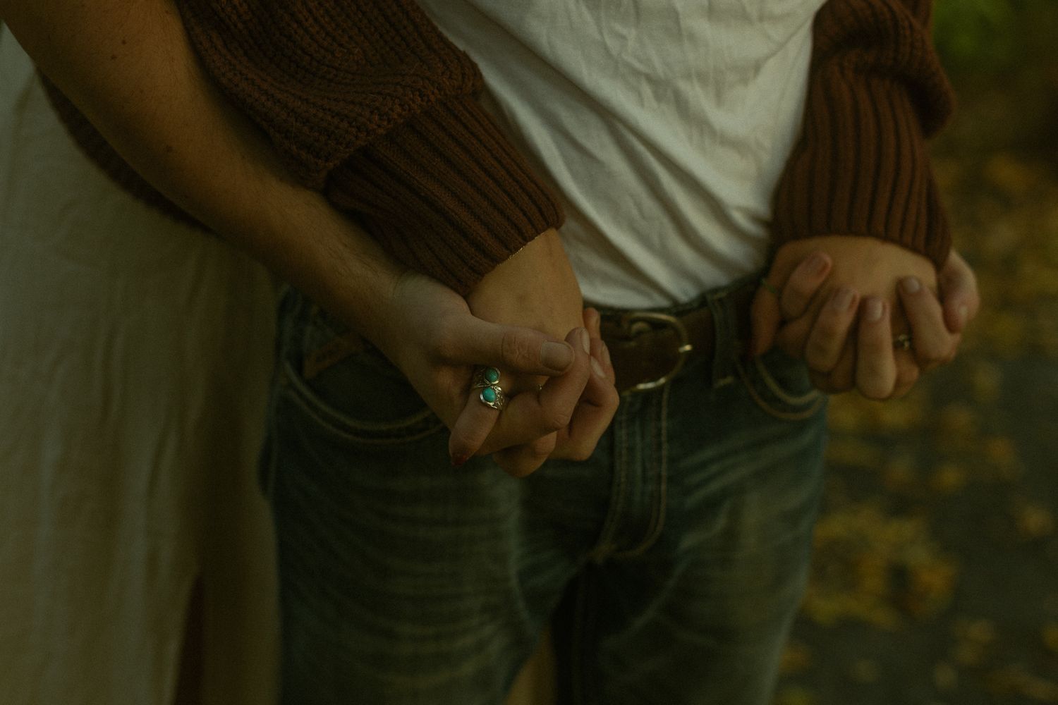Candid family photo showing hands and casual clothing against natural outdoor background.
