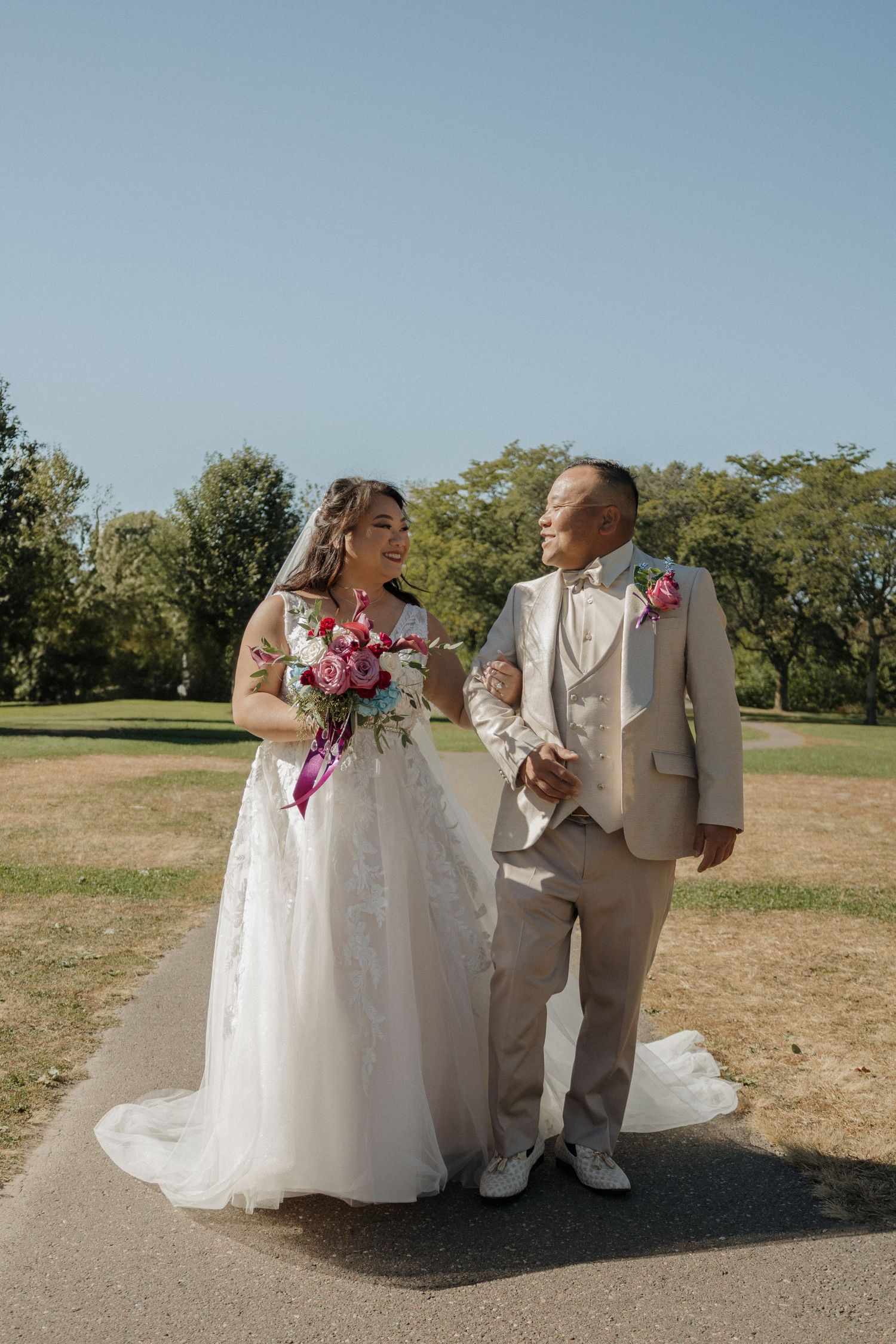 A wedding couple shares a romantic moment in a series of outdoor photos wearing white dress and tan suit.