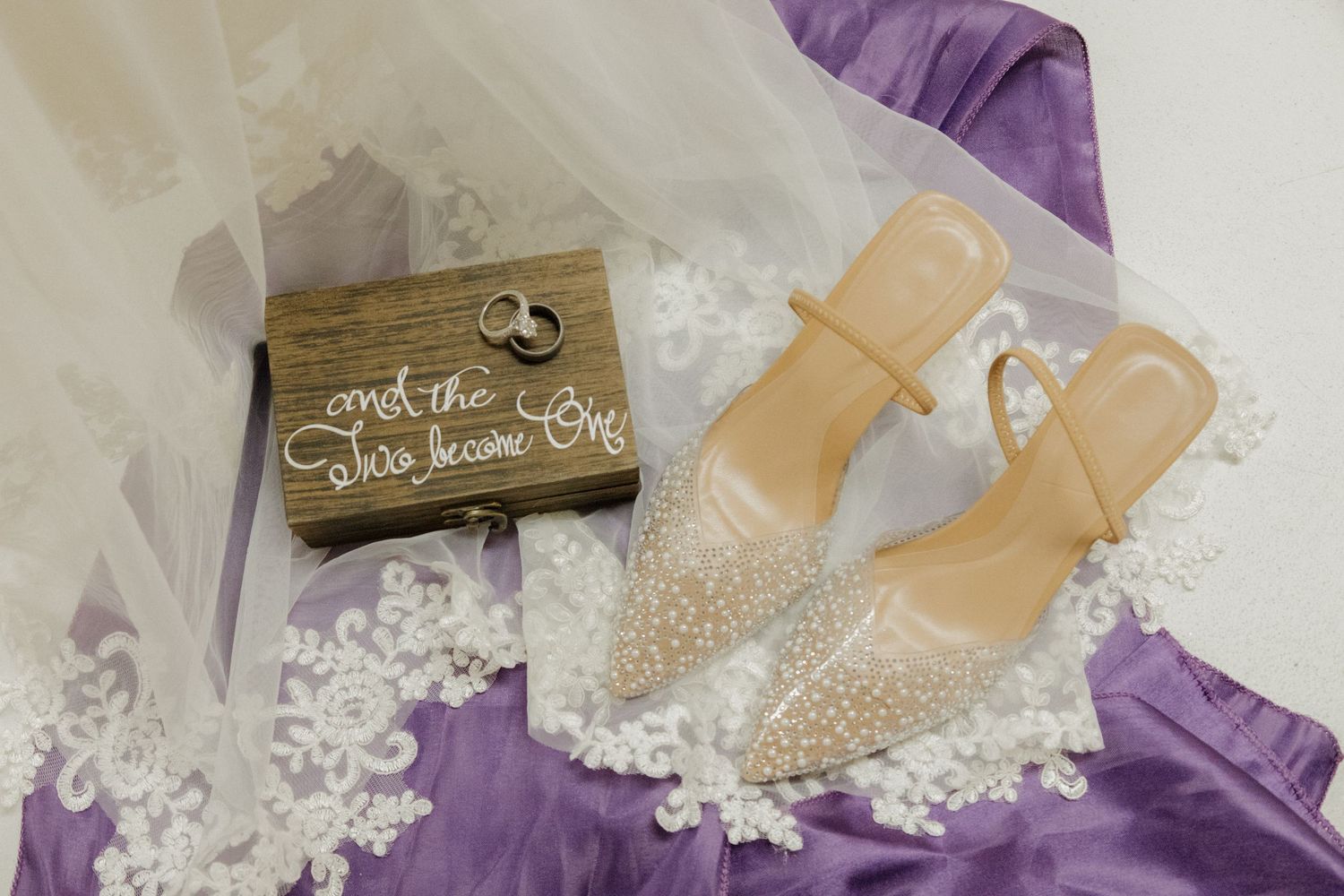 Purple and white wedding decor elements including ribbons, lace, and decorative details arranged on a light surface.