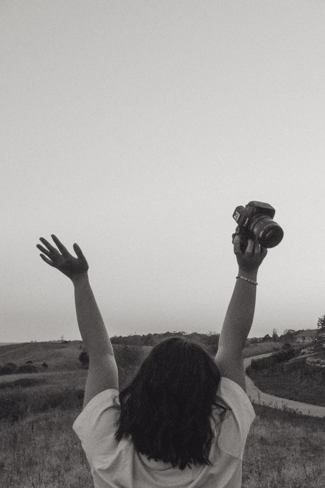 A black and white panoramic sequence shows raised hands against a rural landscape with fields and sky.