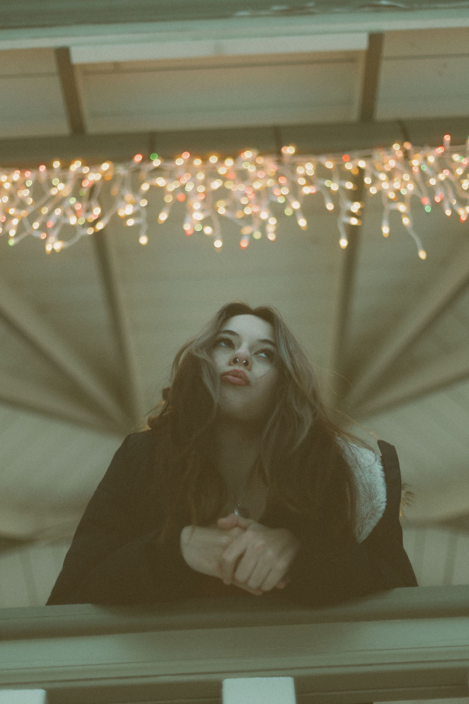 A dreamy artistic photo series showing a person lying down under twinkling string lights with a moody atmosphere.