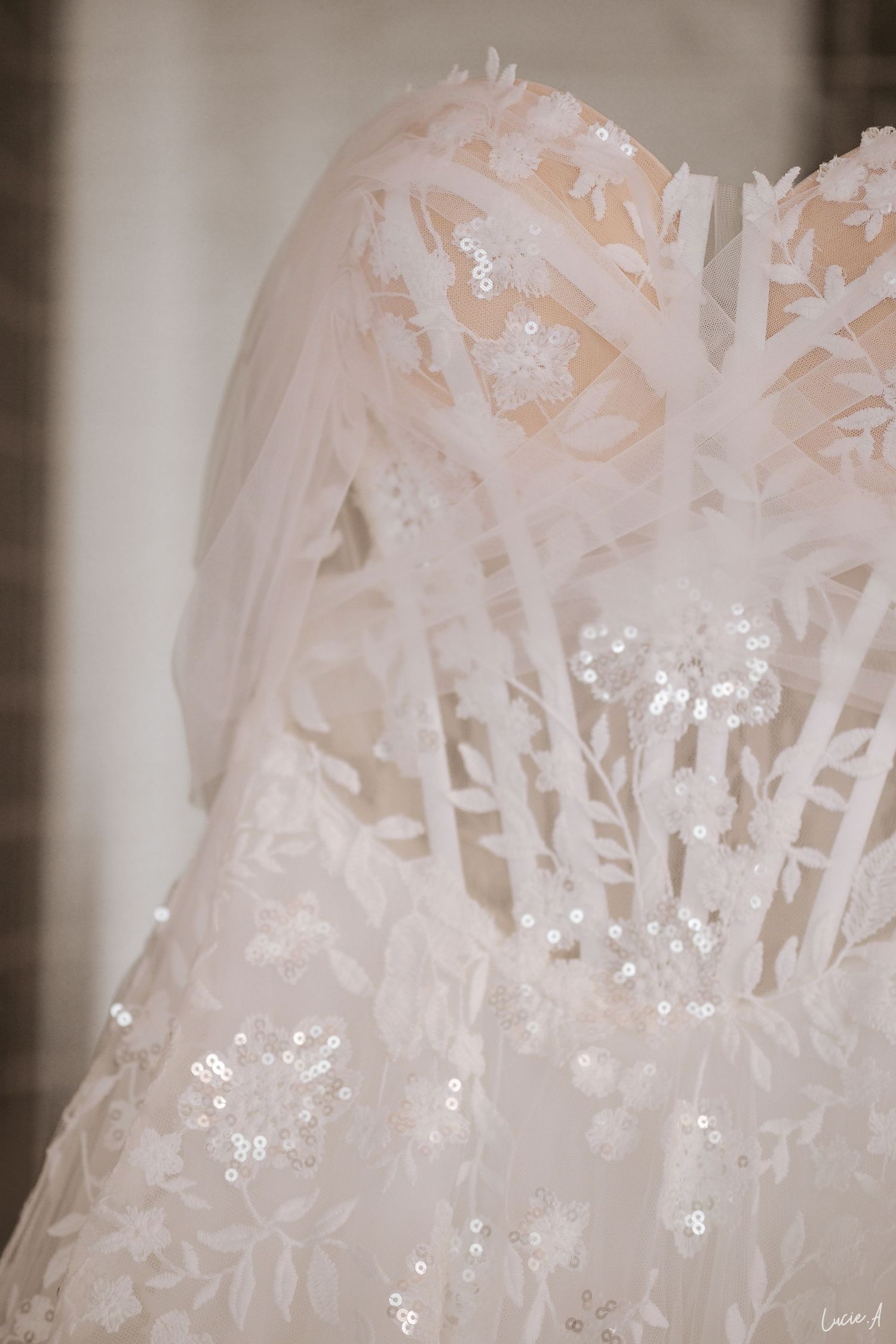 Gros plan sur une élégante robe de mariée blanche ornée de dentelle florale délicate, de sequins et d'un voile de tulle transparent.