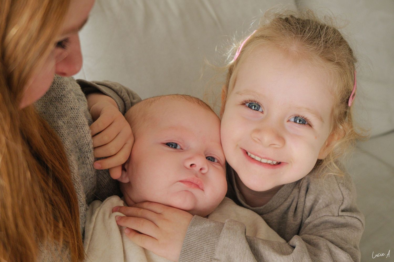 Portrait de famille avec la grande soeur tenant son petit frère nouveau né sous le regard de leur maman