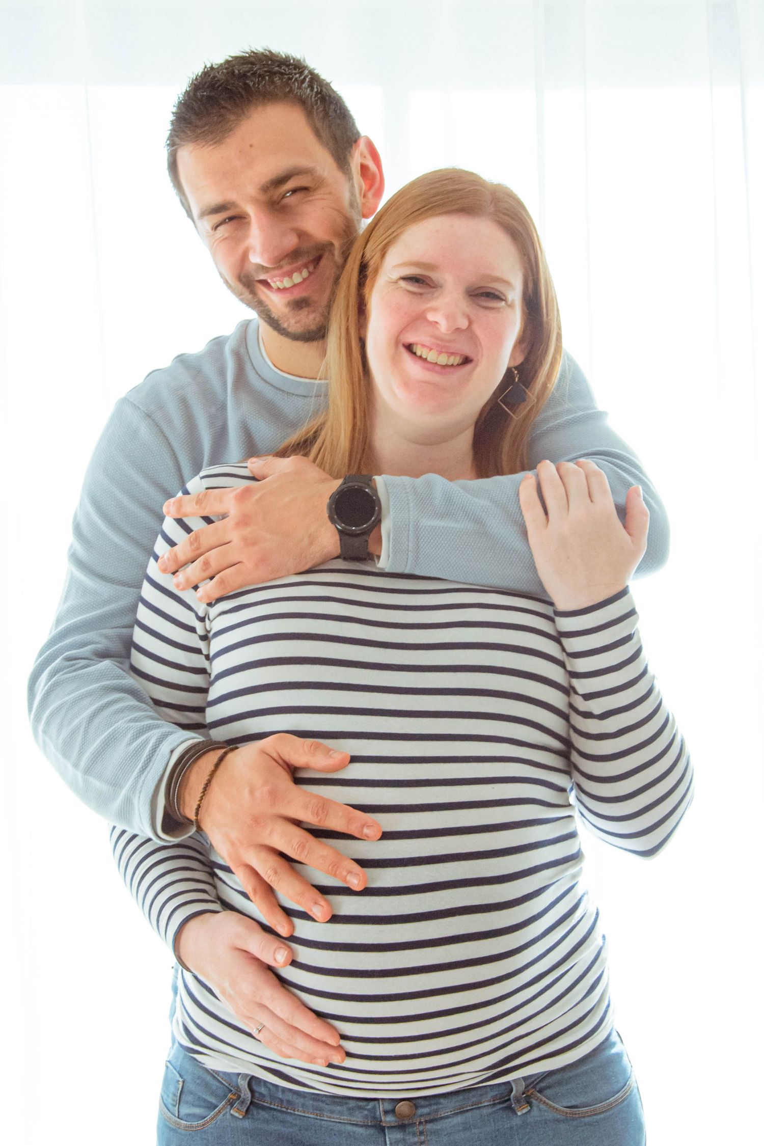 Portrait couleur séance grossesse, prise de face avec le futur papa derrière la maman, la main sur le ventre, à Ronchin près de Lille