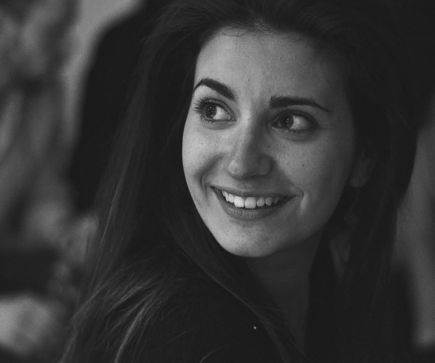 Portrait noir et blanc d'une femme brune souriante regardant hors cadre, prise à Ronchin