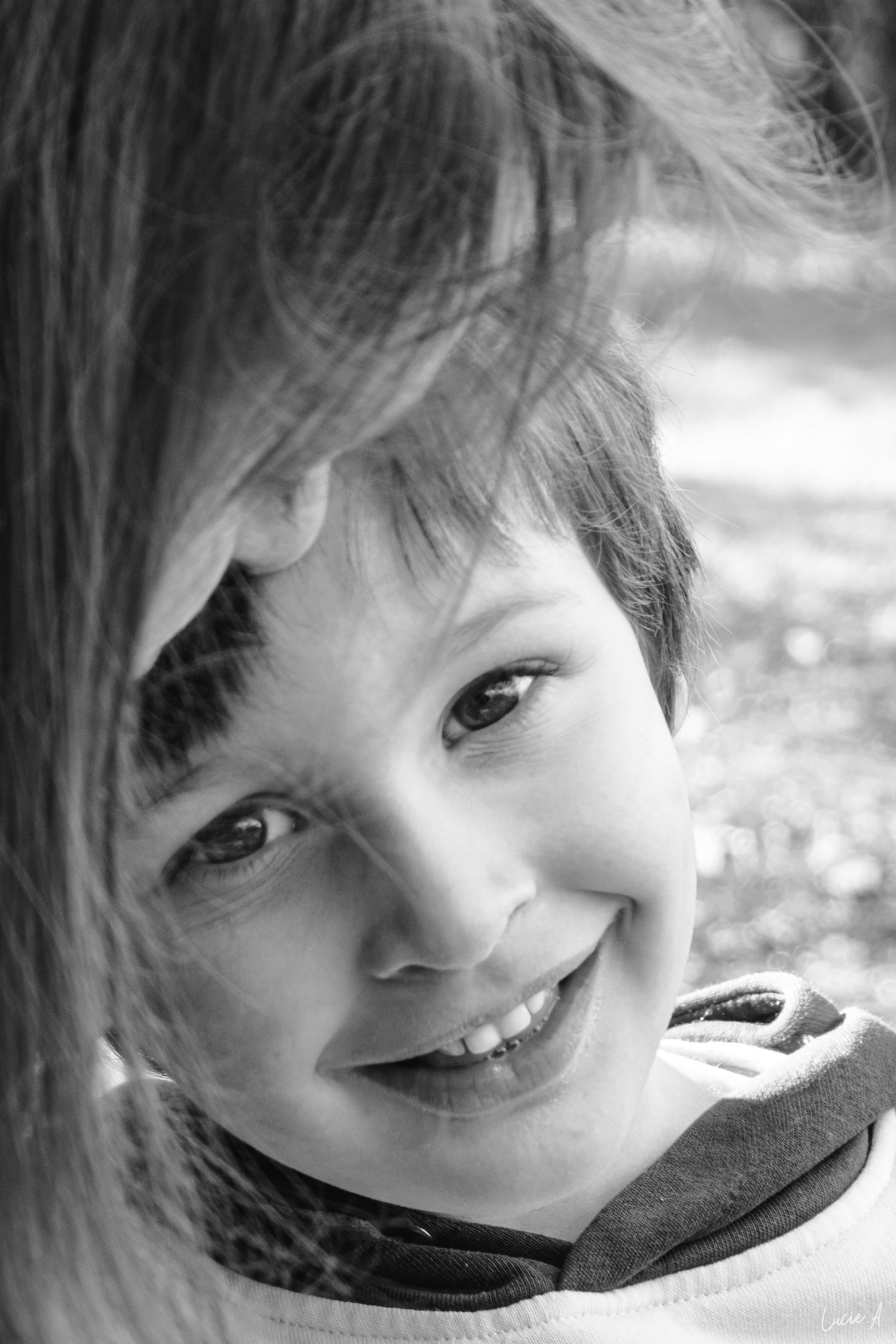 portrait en noir et blanc d'un petit garçon souriant dans un parc de jeux à Lille