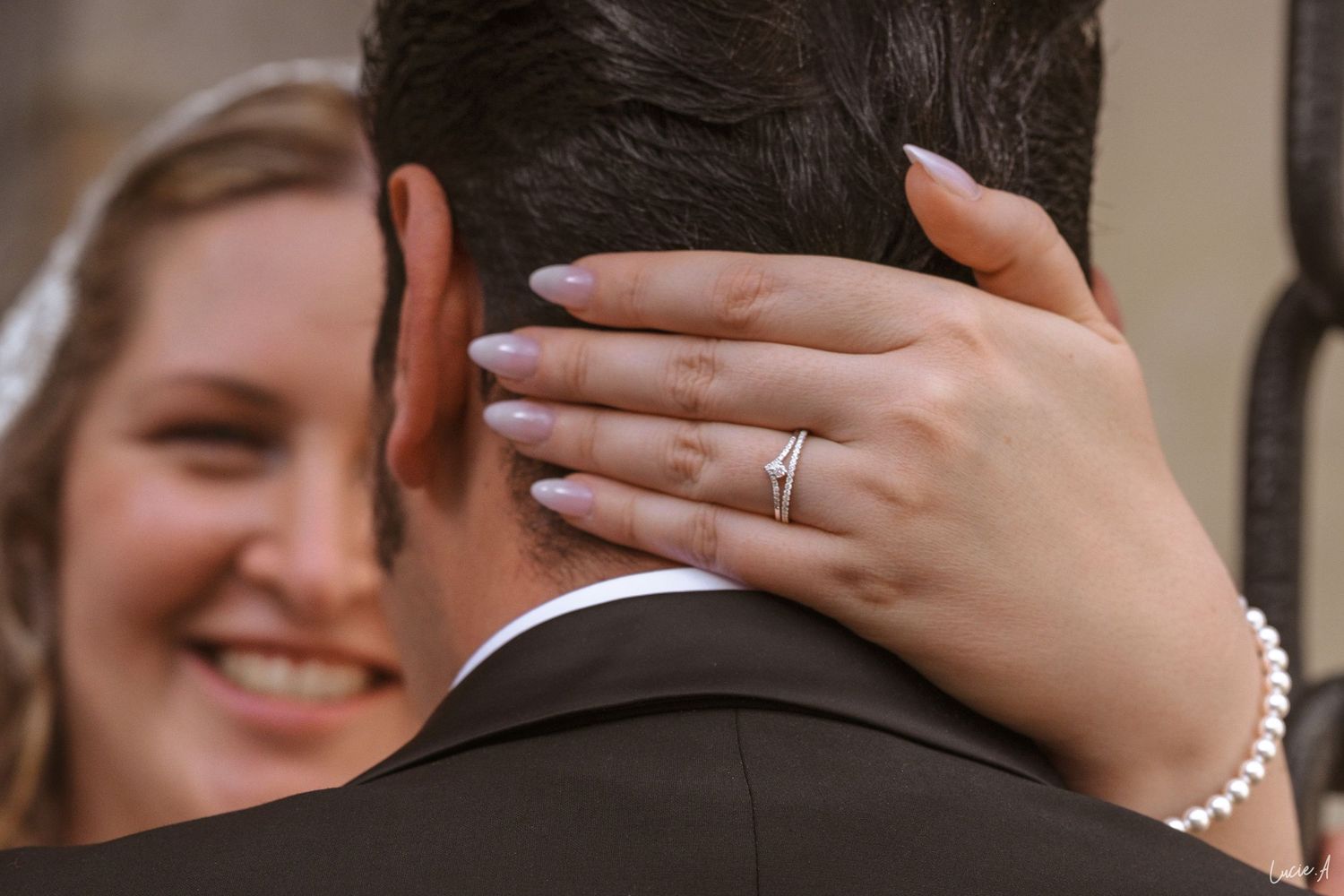 La mariée sourit, arborant un bracelet de perles et une alliance en diamants au cou du marié lors de la cérémonie de mariage.