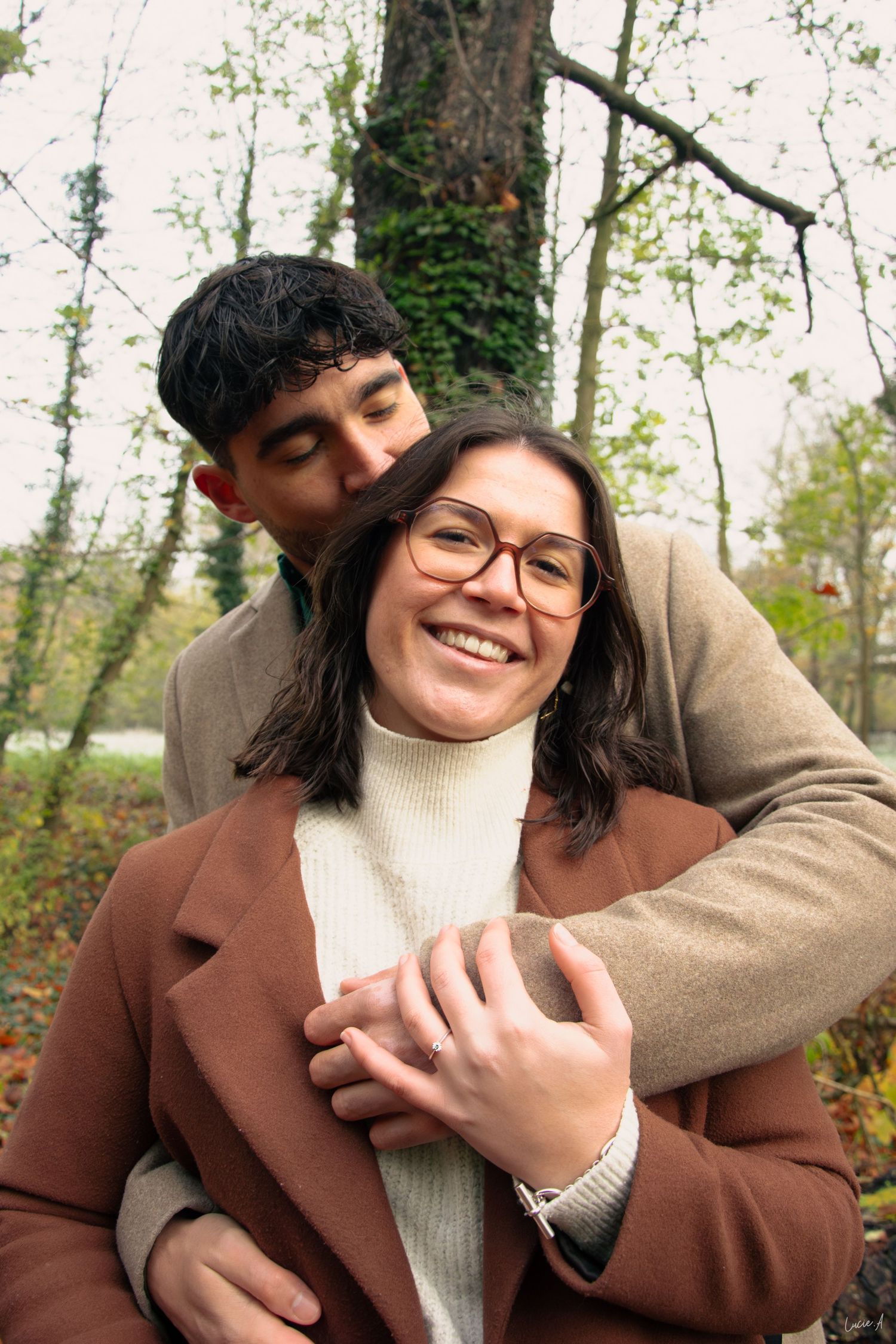 Portrait couleur séance d'engagement, l'homme se tient derrière sa compagne, un bras autour d'elle, séance en extérieur à Lille