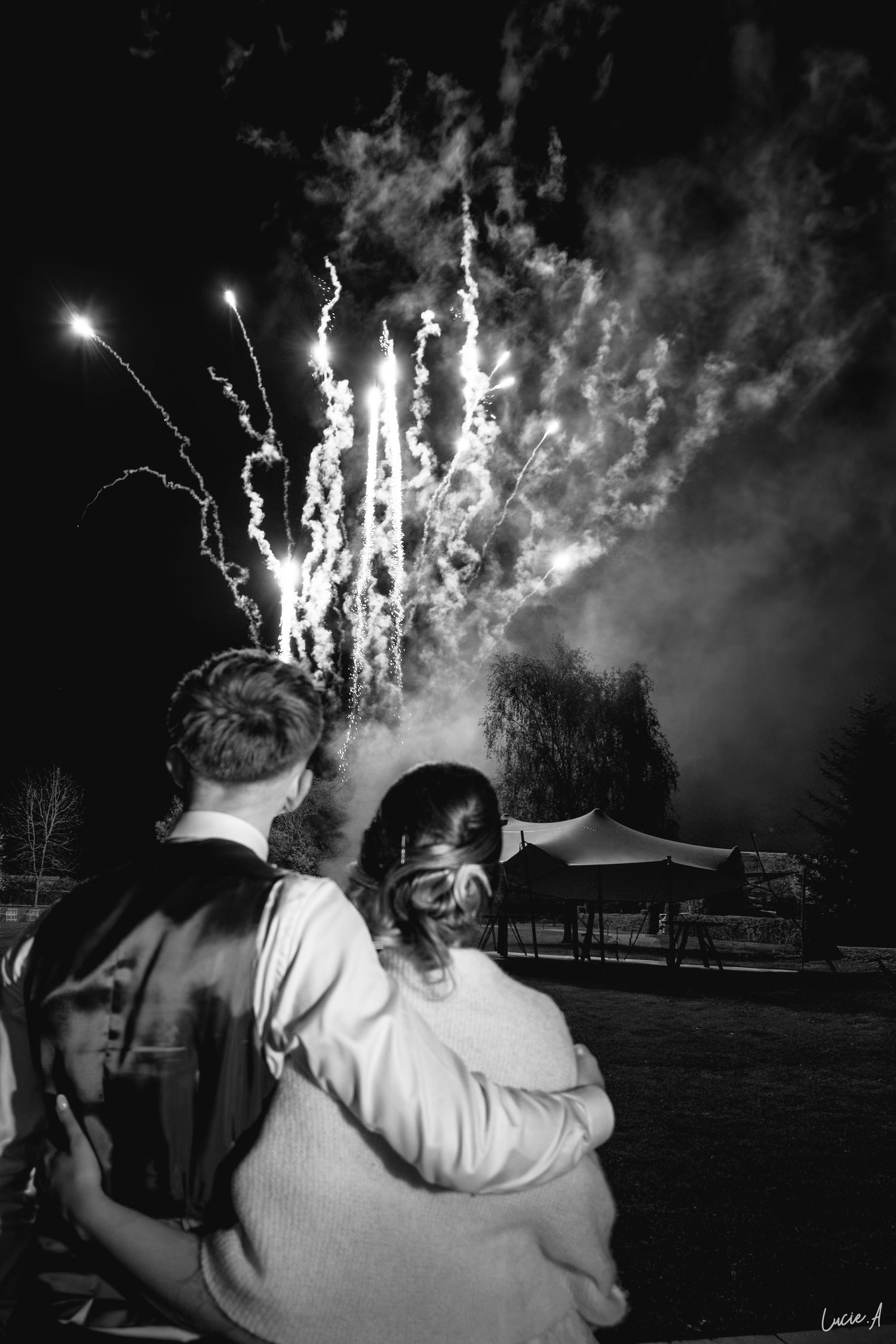 un jeune couple de marié regardant un feu d'artifice à leur mariage, photo en noir et blanc