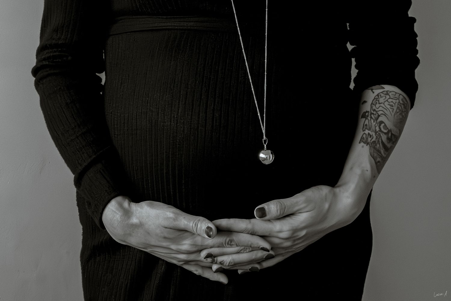 Portrait noir et blanc grossesse, gros plan de face la mère enlaçant son ventre, capté à Ronchin