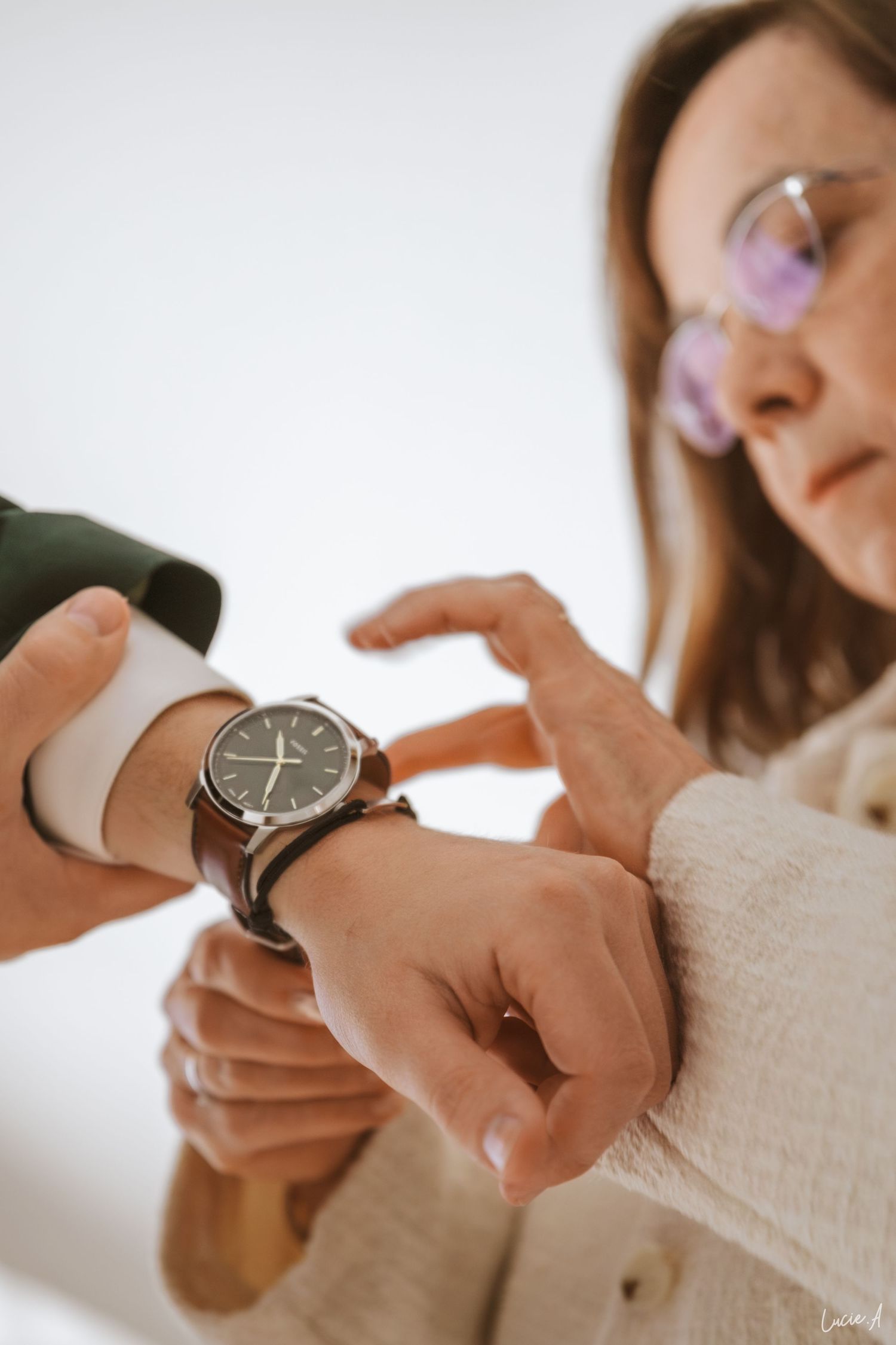 la maman du marié portant des lunettes vérifie une montre en cuir marron au poignet du marié lors des préparatifs d'un mariage.