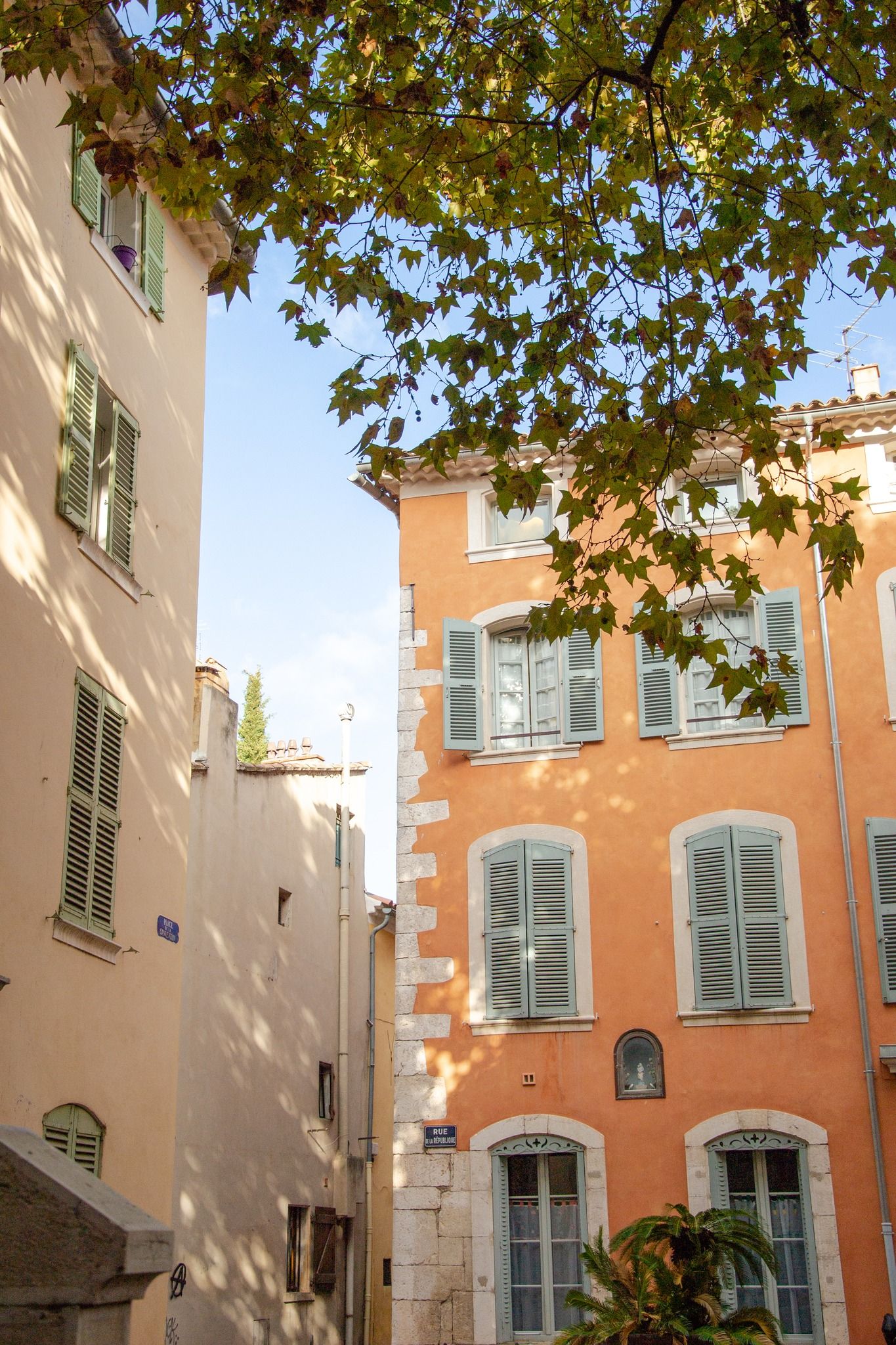 Prise couleur d'une façade d'un immeuble de style méditerranéen, de couleur orange, avec des fenêtres à volets traditionnelles